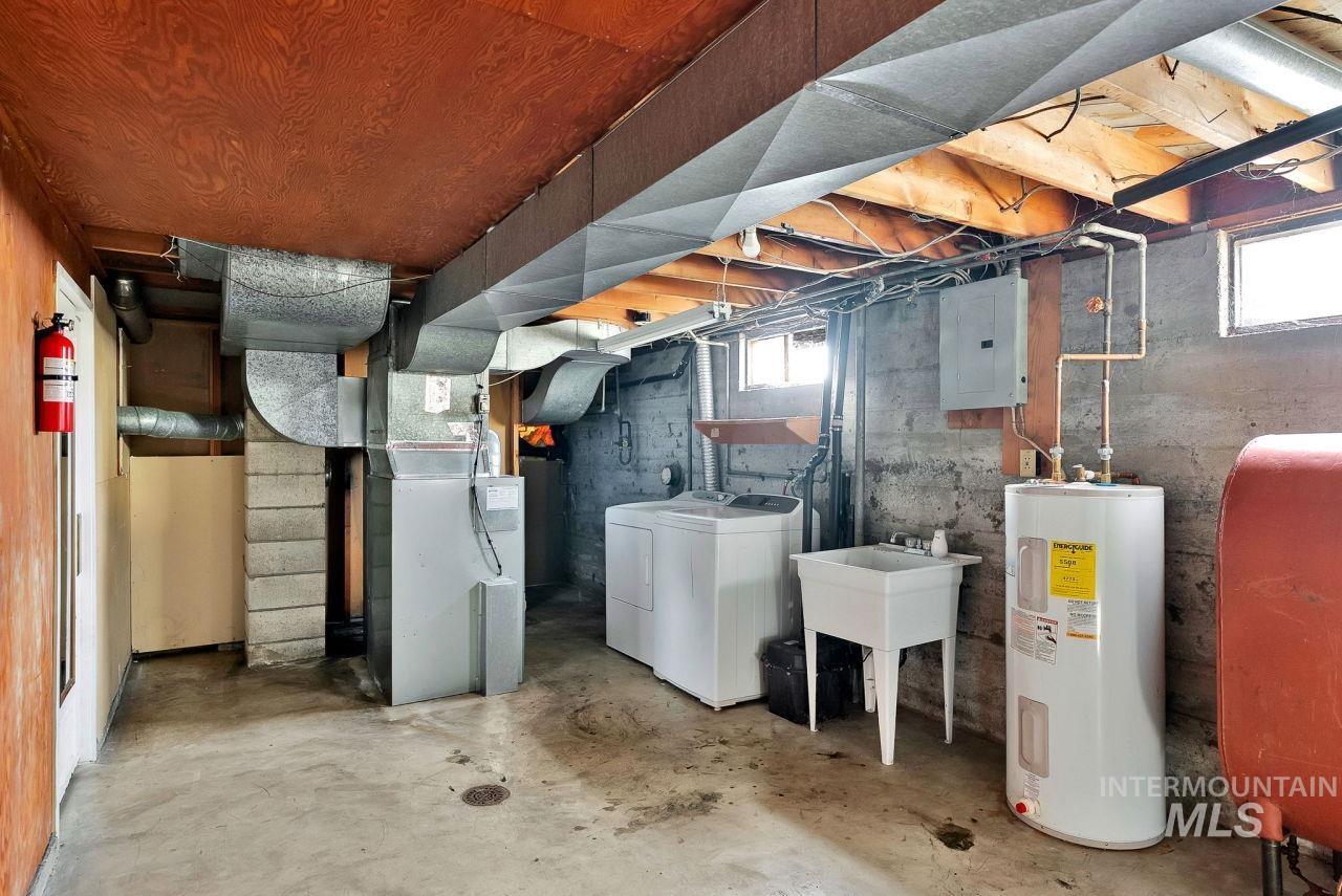 Below grade area featuring electric water heater, electric panel, oil tank, heating unit, and washing machine and dryer
