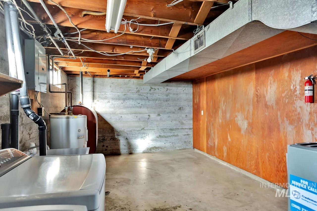 Unfinished below grade area featuring washer / clothes dryer, electric panel, oil tank, and electric water heater