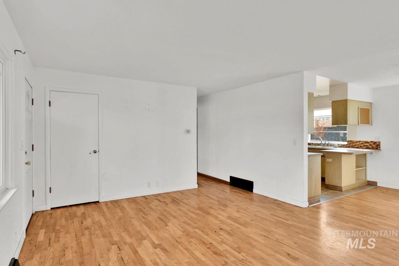 Unfurnished living room with light wood-type flooring and baseboards