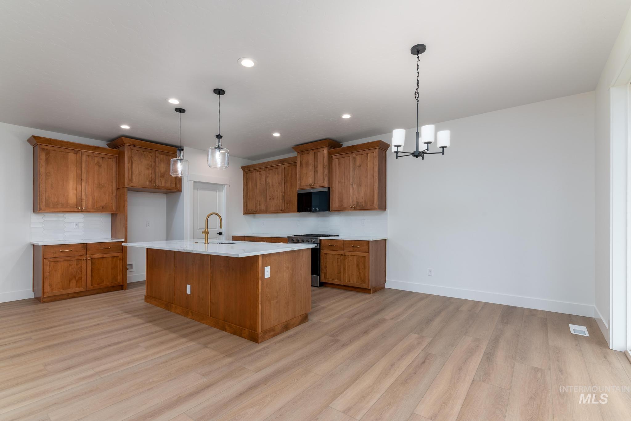 Kitchen featuring brown cabinetry, pendant lighting, a chandelier, and recessed lighting
