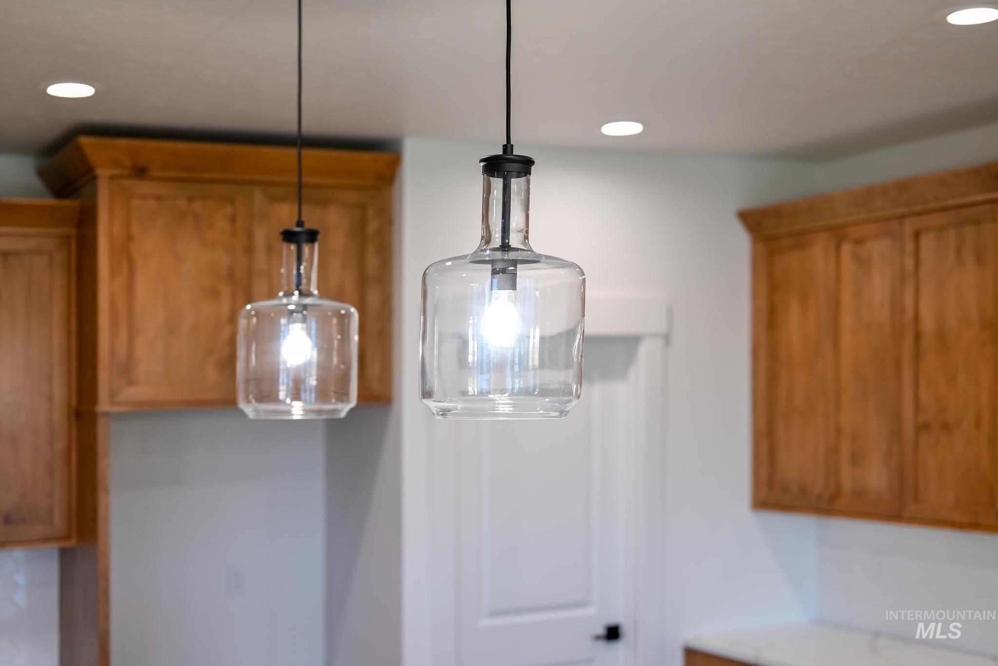 Kitchen view of brown cabinets, hanging light fixtures, and recessed lighting
