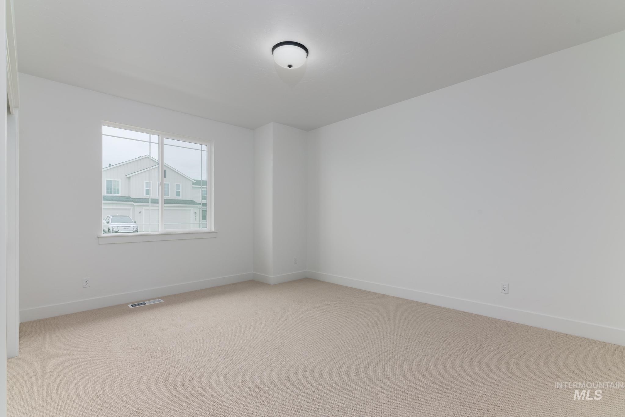 Empty room featuring light colored carpet and baseboards