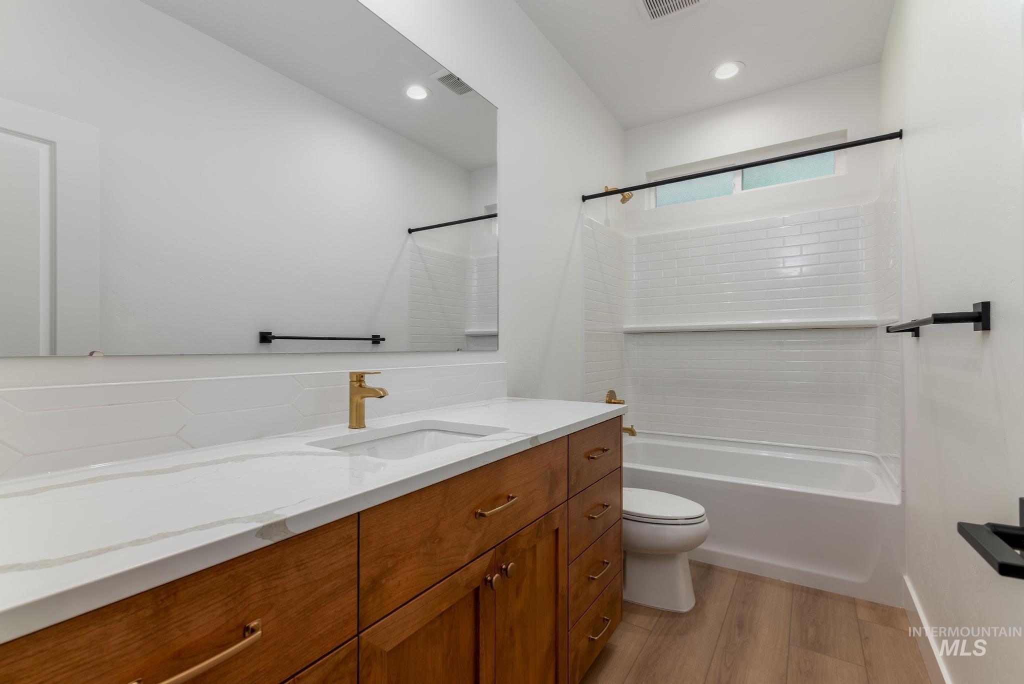 Bathroom featuring vanity, shower / tub combination, light wood-style floors, and recessed lighting