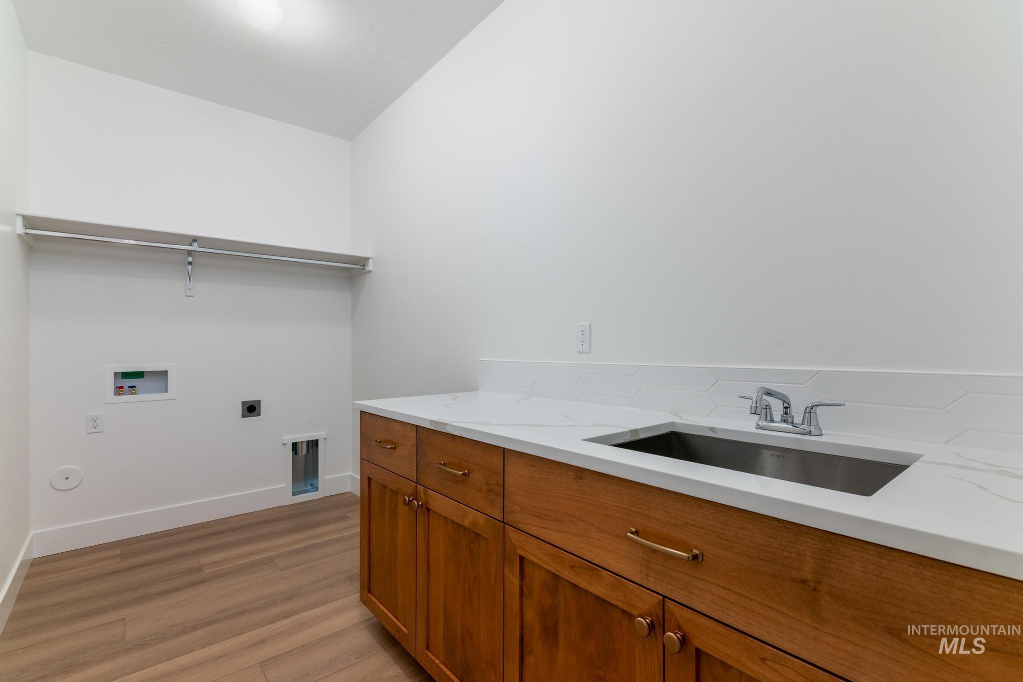 Washroom featuring hookup for an electric dryer, light wood-type flooring, washer hookup, and cabinet space