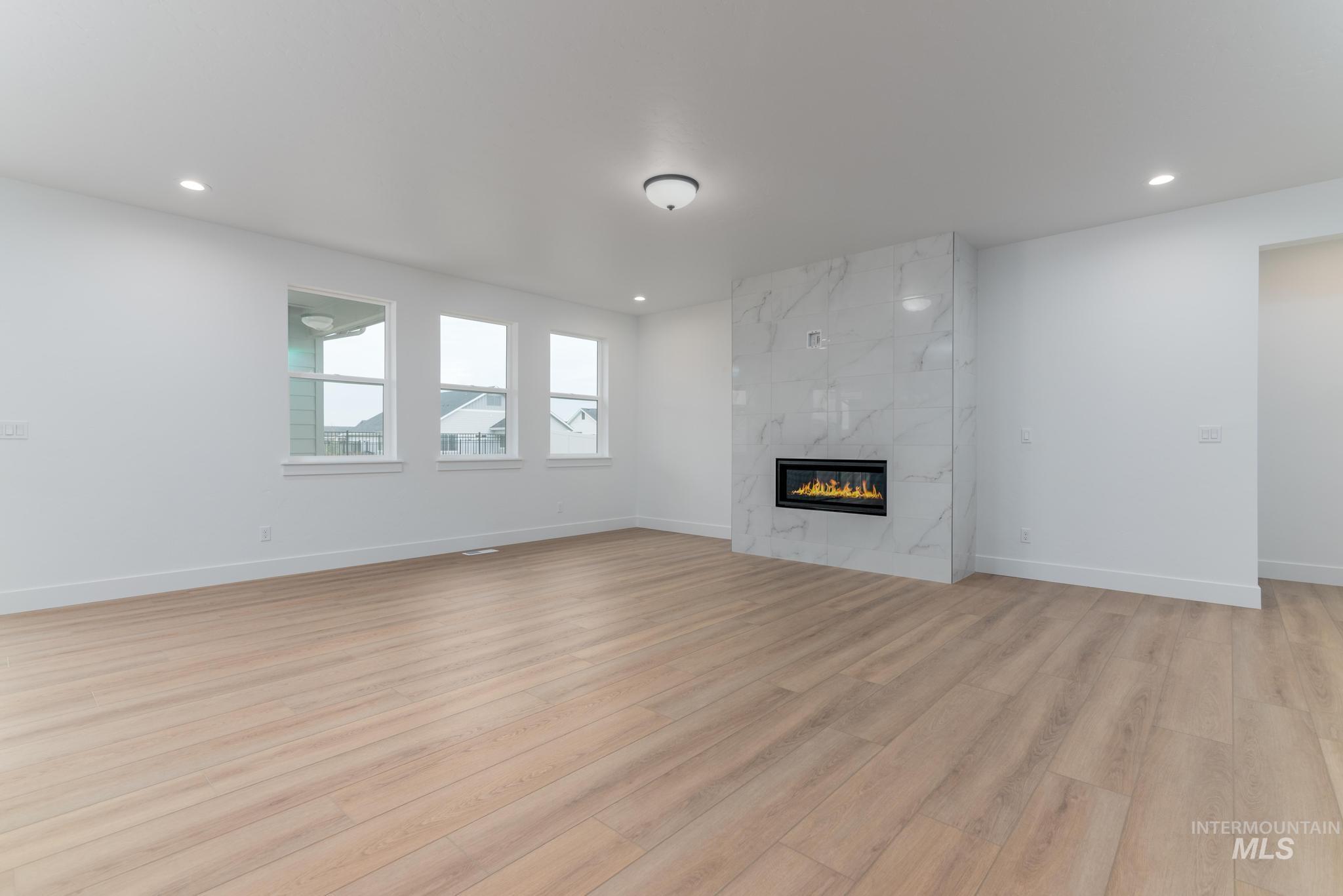 Unfurnished living room with light wood finished floors, a fireplace, and recessed lighting