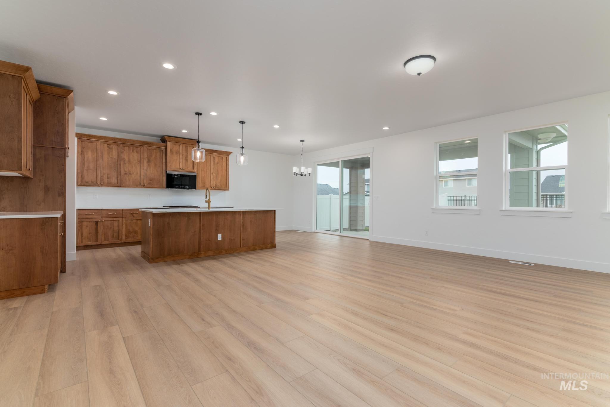 Kitchen featuring brown cabinets, pendant lighting, open floor plan, light countertops, and recessed lighting