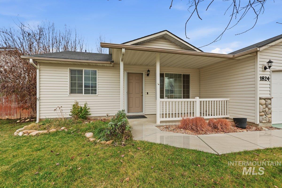 View of front of property featuring covered porch, an attached garage, and a front yard