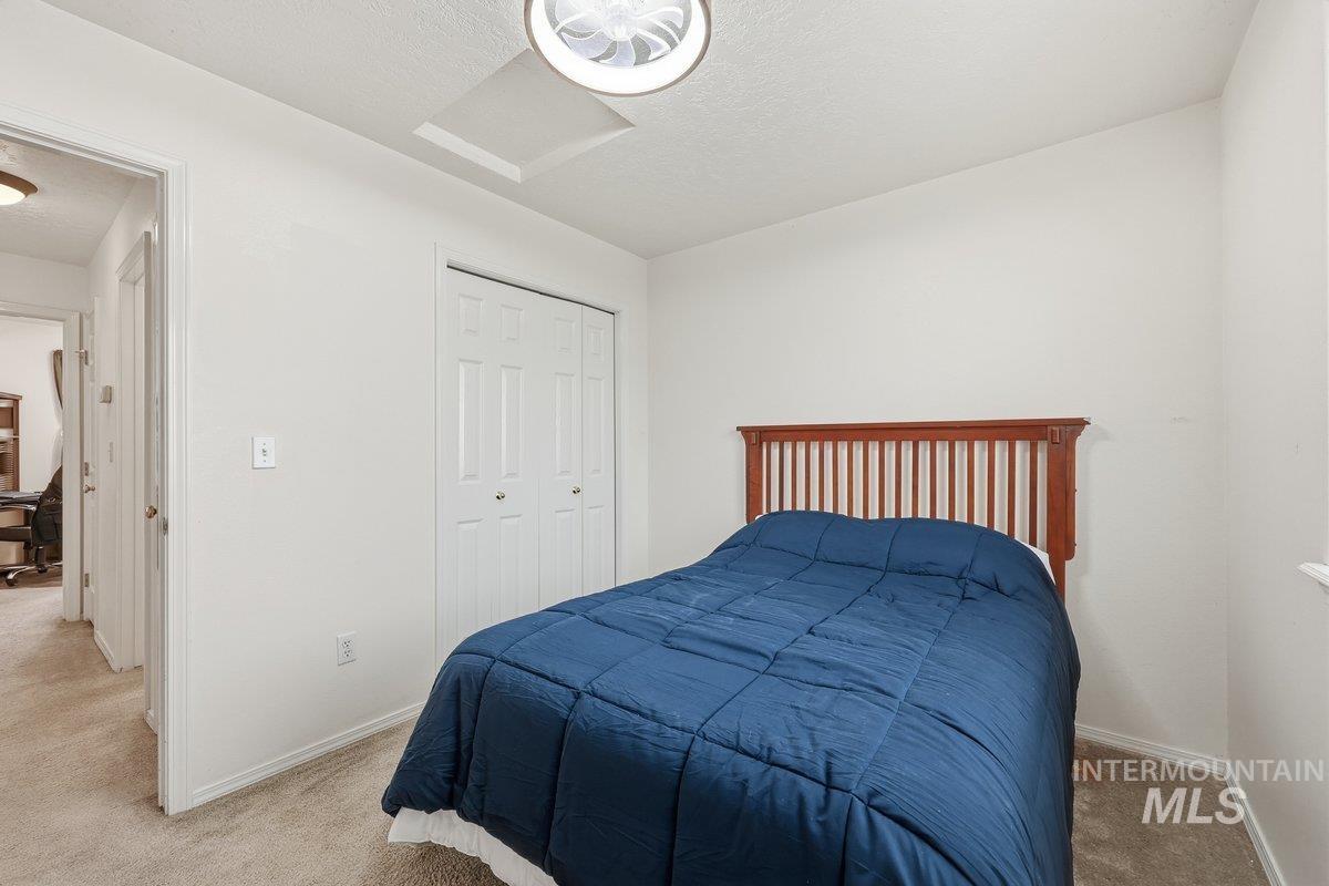 Bedroom with attic access, carpet floors, a closet, and a textured ceiling