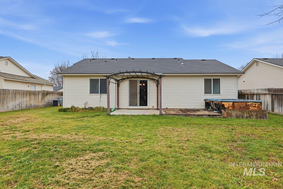 Rear view of house featuring a fenced backyard, roof with shingles, and a patio area