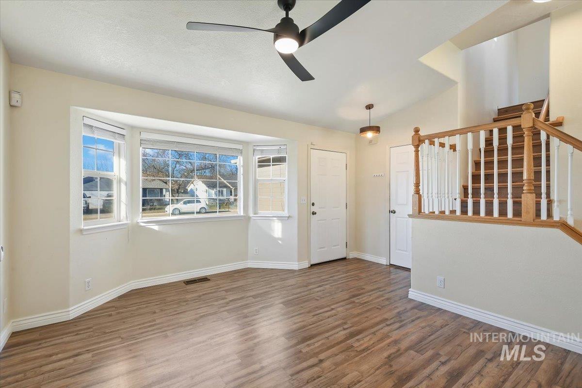 Entryway featuring wood finished floors, stairway, a ceiling fan, and vaulted ceiling