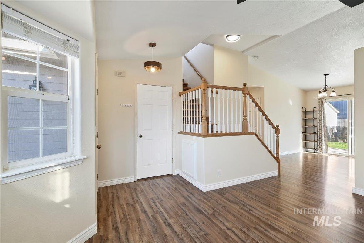 Entrance foyer with dark wood finished floors, stairs, and lofted ceiling