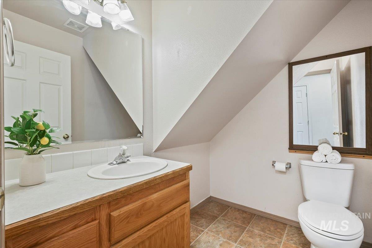 Half bath featuring vanity and lofted ceiling