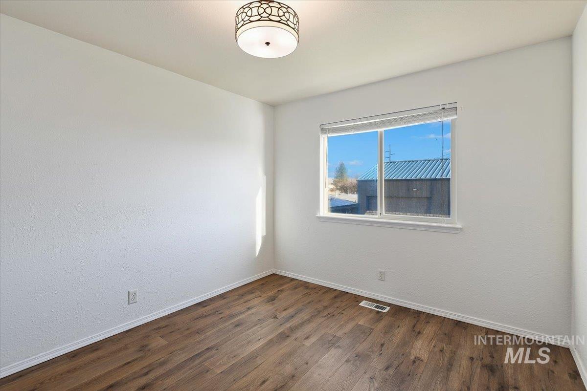 Unfurnished room with dark wood-style floors and baseboards