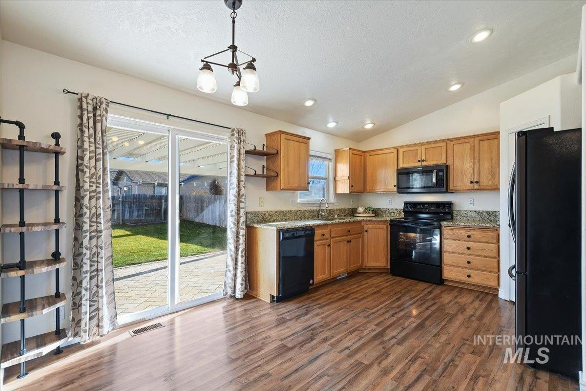 Kitchen with open shelves, black appliances, pendant lighting, vaulted ceiling, and dark wood finished floors