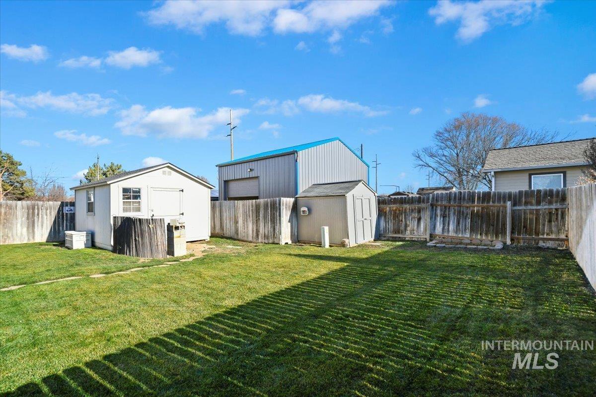 Fenced backyard featuring a storage unit