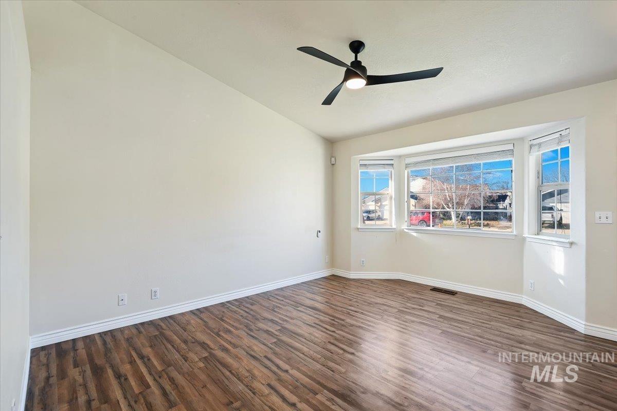 Unfurnished room with lofted ceiling, dark wood finished floors, and a ceiling fan