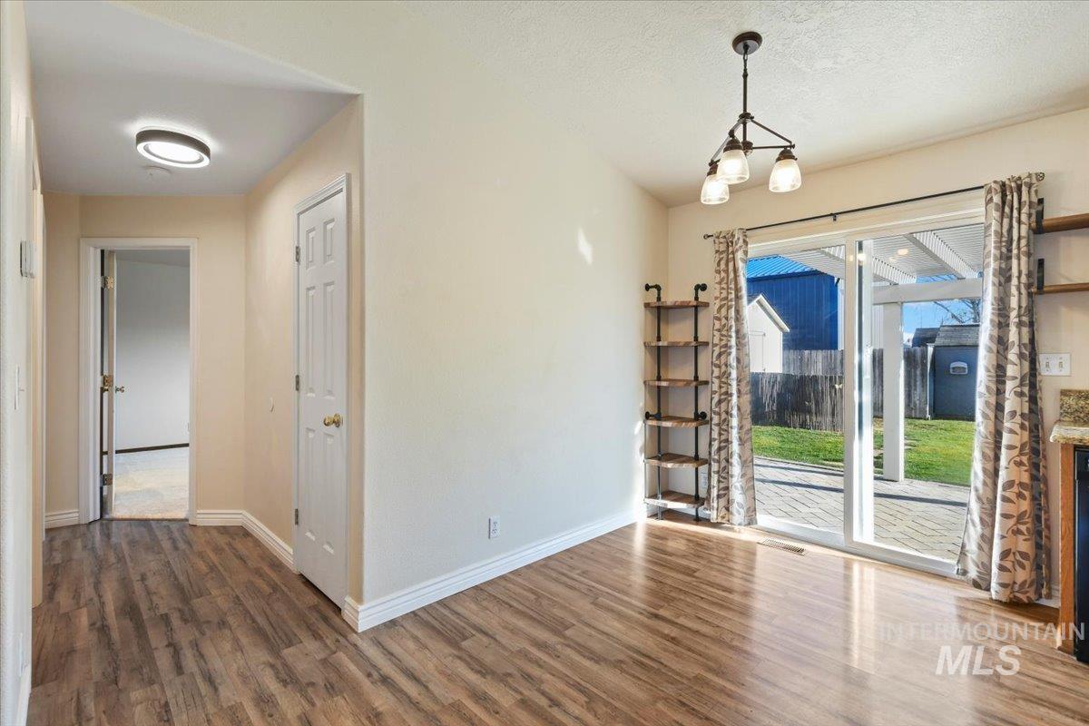 Unfurnished dining area with dark wood-type flooring, a chandelier, and a textured ceiling