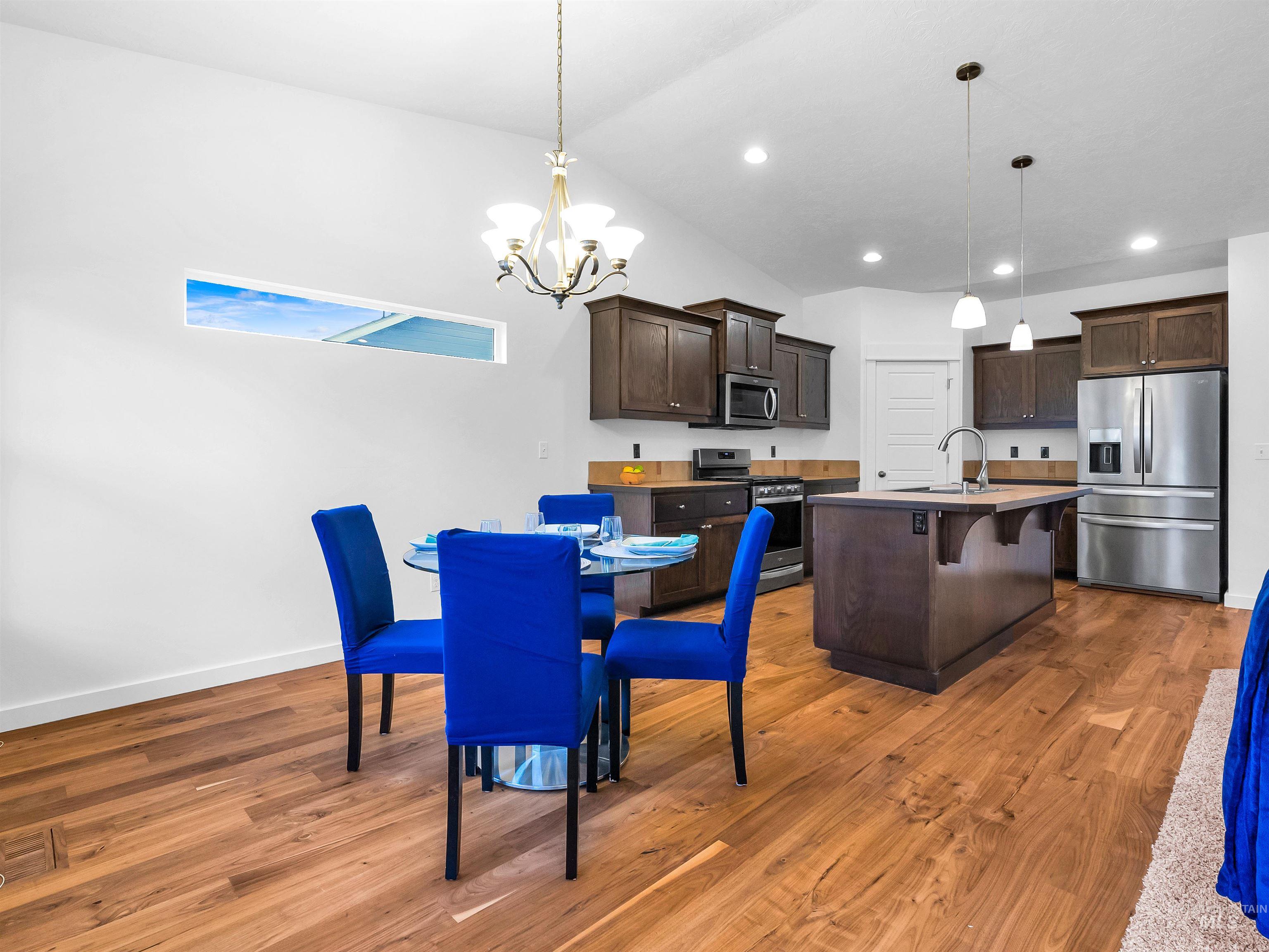 Dining area featuring light wood-style floors, vaulted ceiling, a chandelier, and recessed lighting