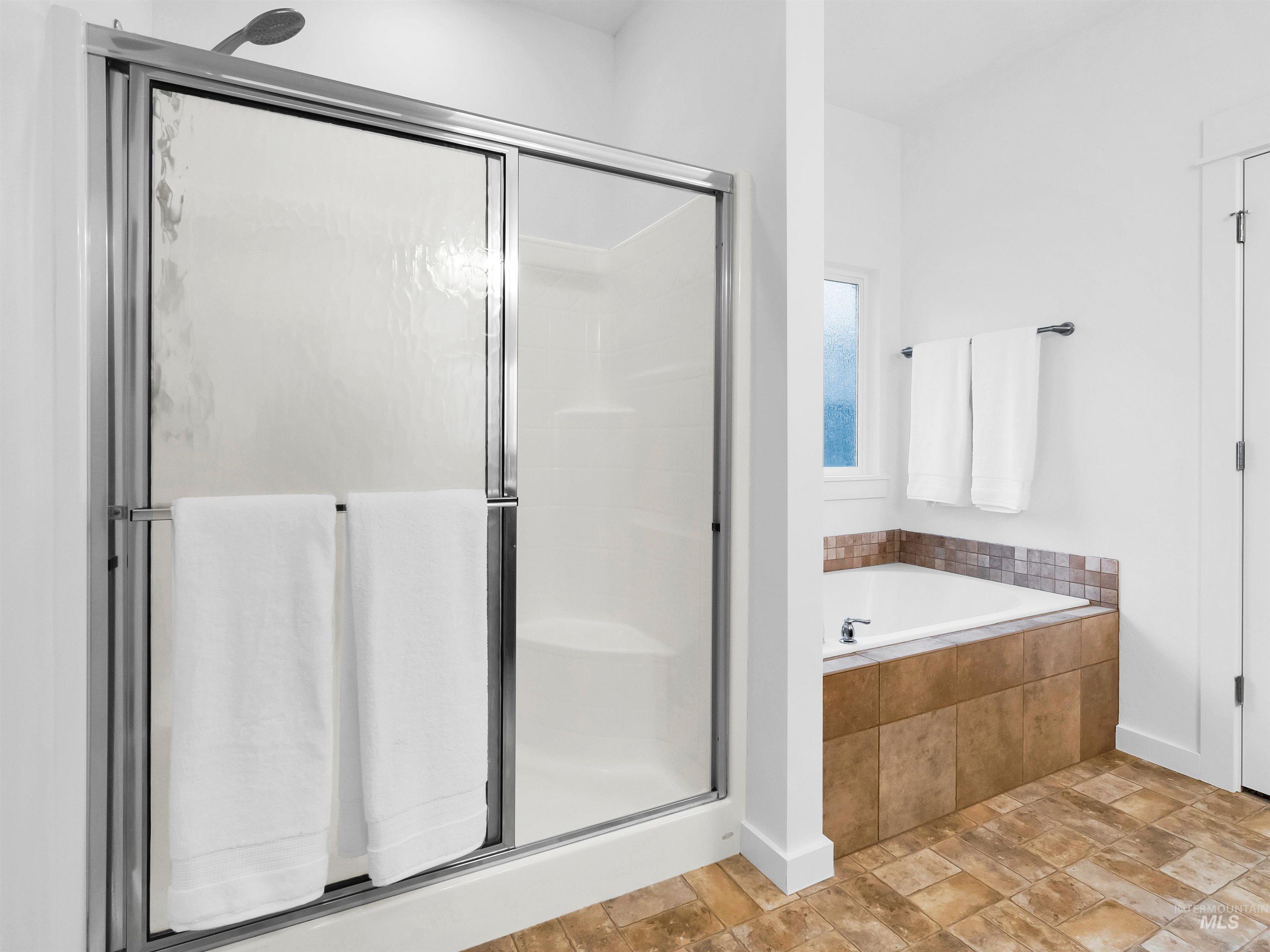 Bathroom featuring stone finish floors, a bath, and a shower stall