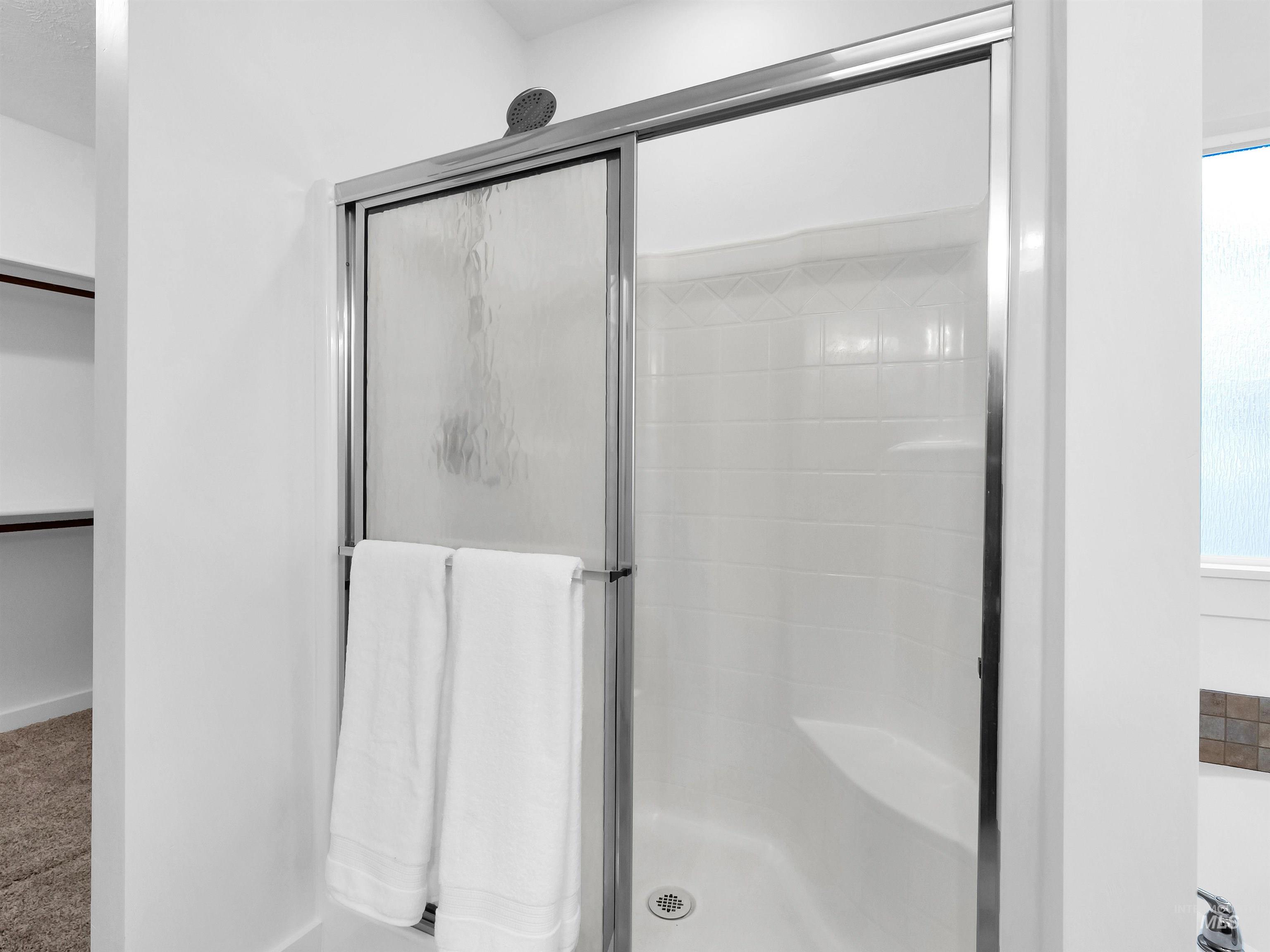 Bathroom with a stall shower, a walk in closet, and carpet