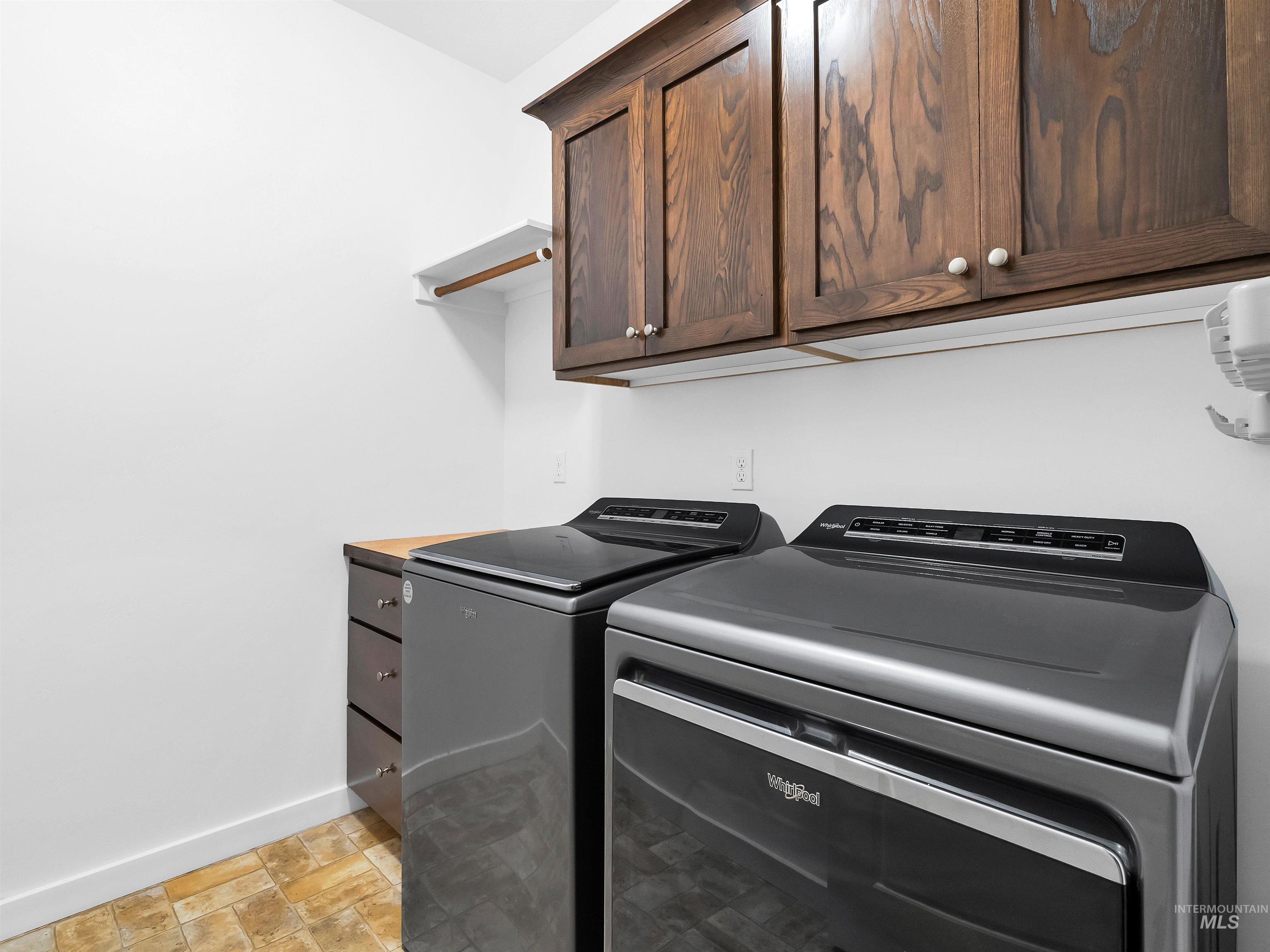 Laundry room with cabinet space, washer and dryer, and stone finish floors