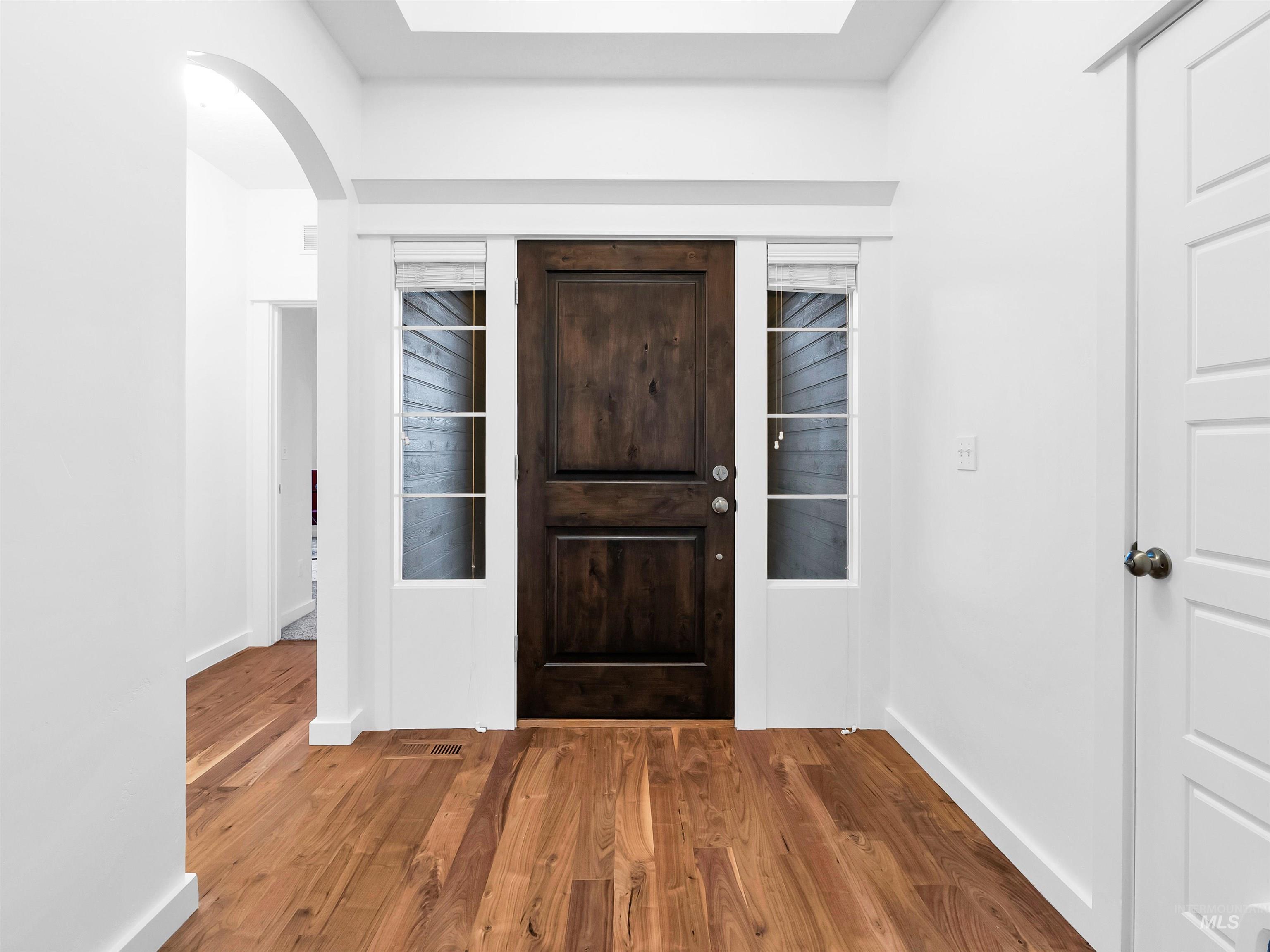 Foyer featuring wood finished floors and arched walkways