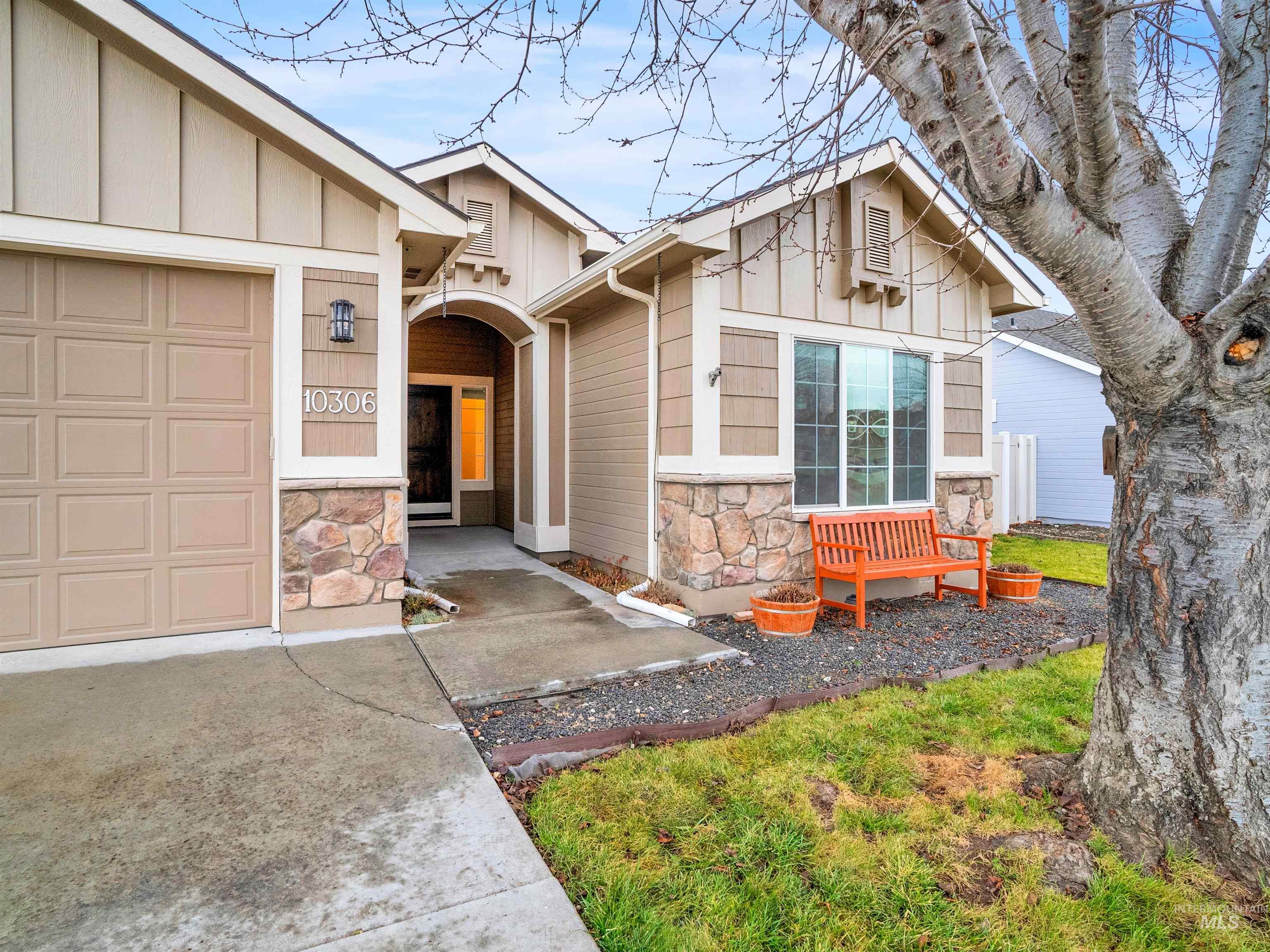 View of front of house with stone siding, a garage, and board and batten siding