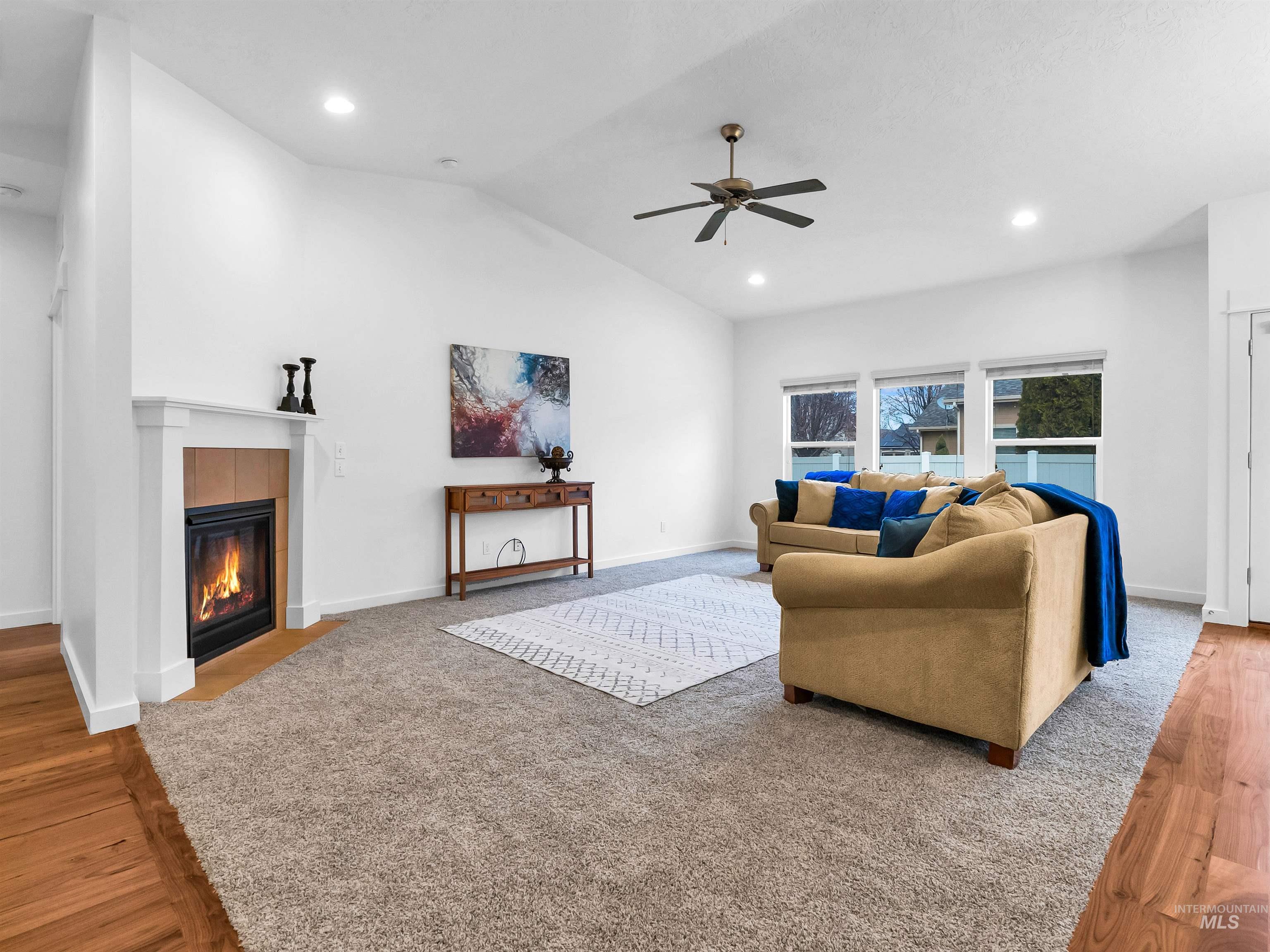 Living room featuring vaulted ceiling, a tile fireplace, light wood-type flooring, recessed lighting, and ceiling fan