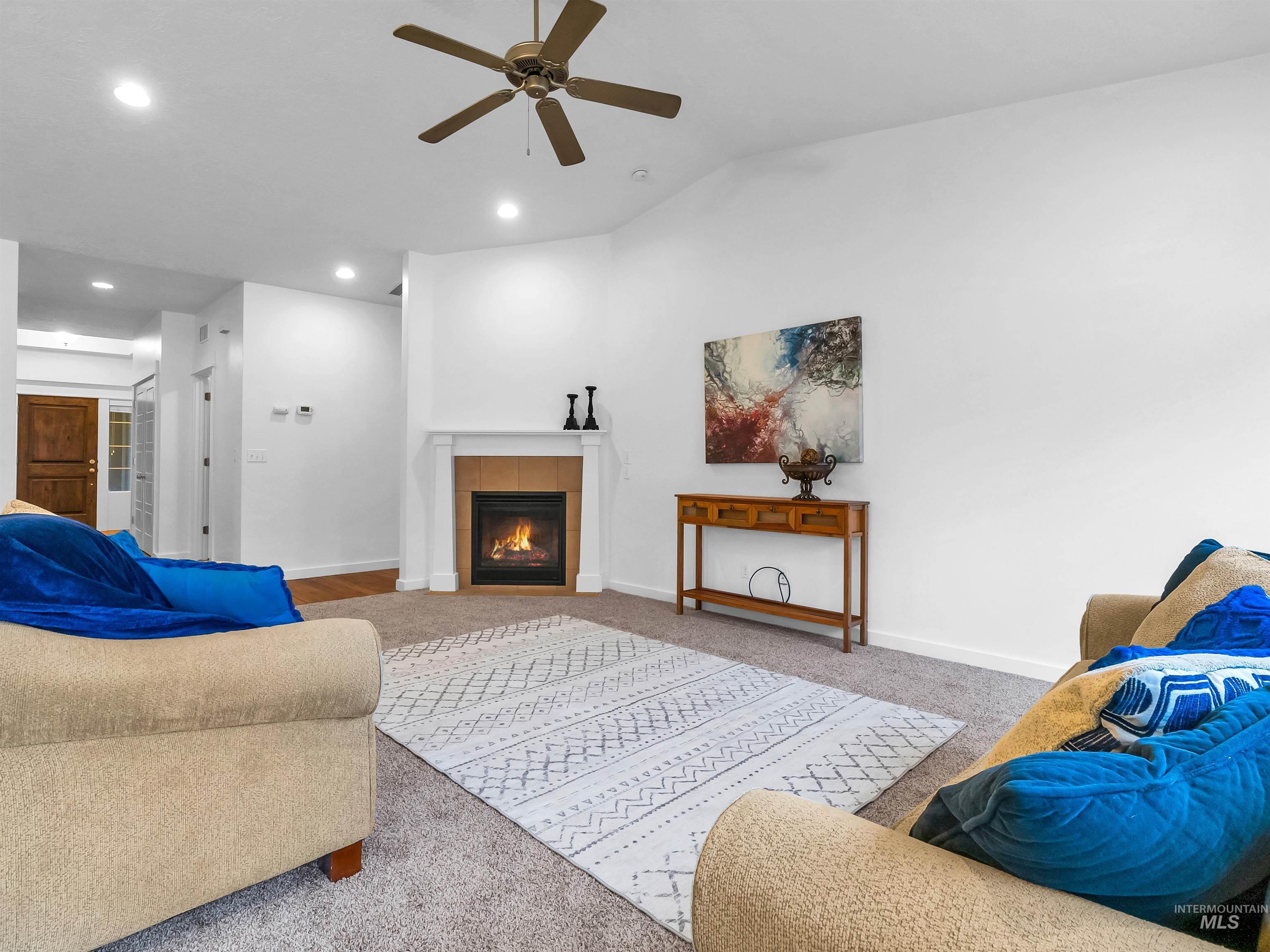 Living room with vaulted ceiling, a tiled fireplace