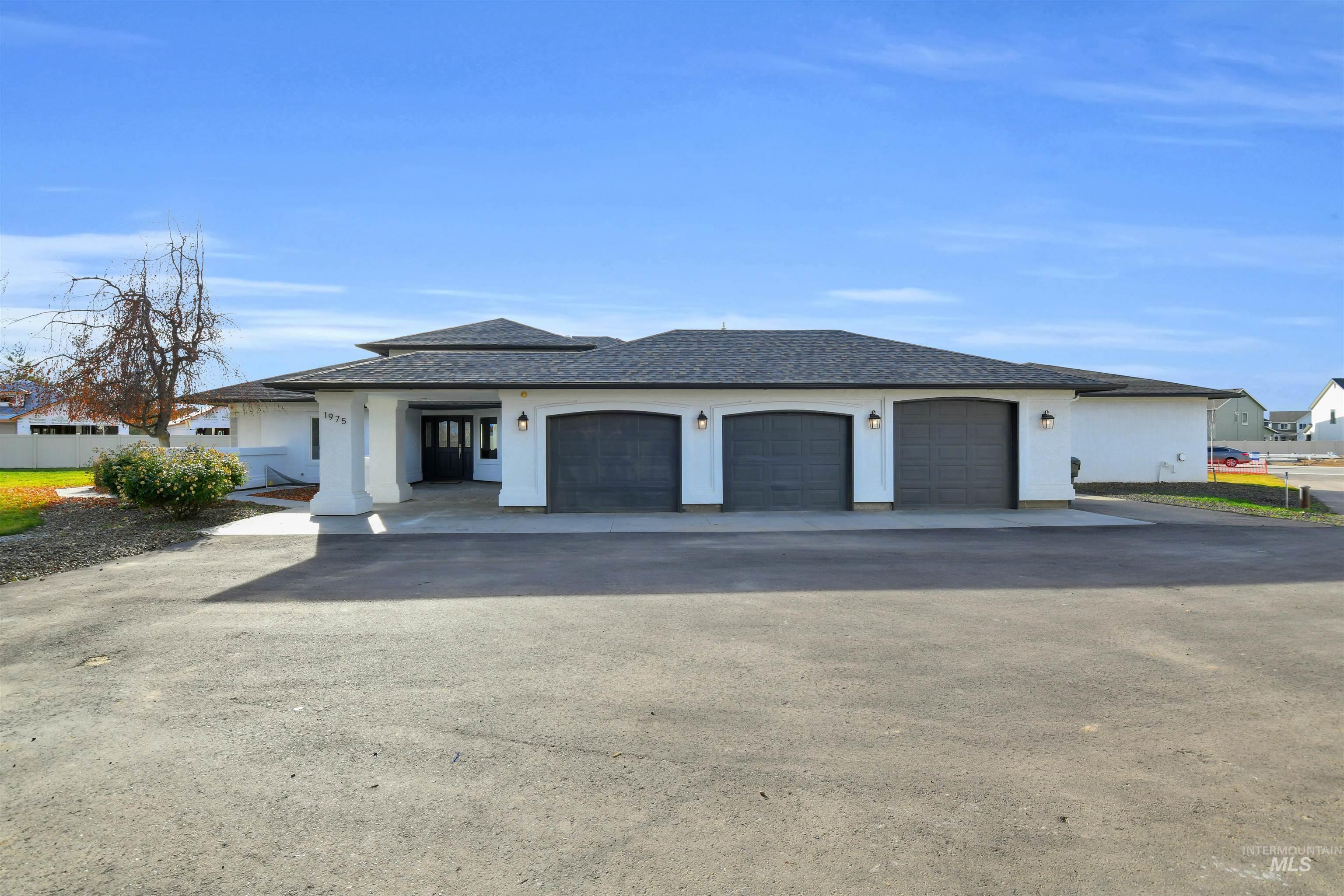 View of front facade with asphalt driveway, stucco siding, an attached garage, and a shingled roof