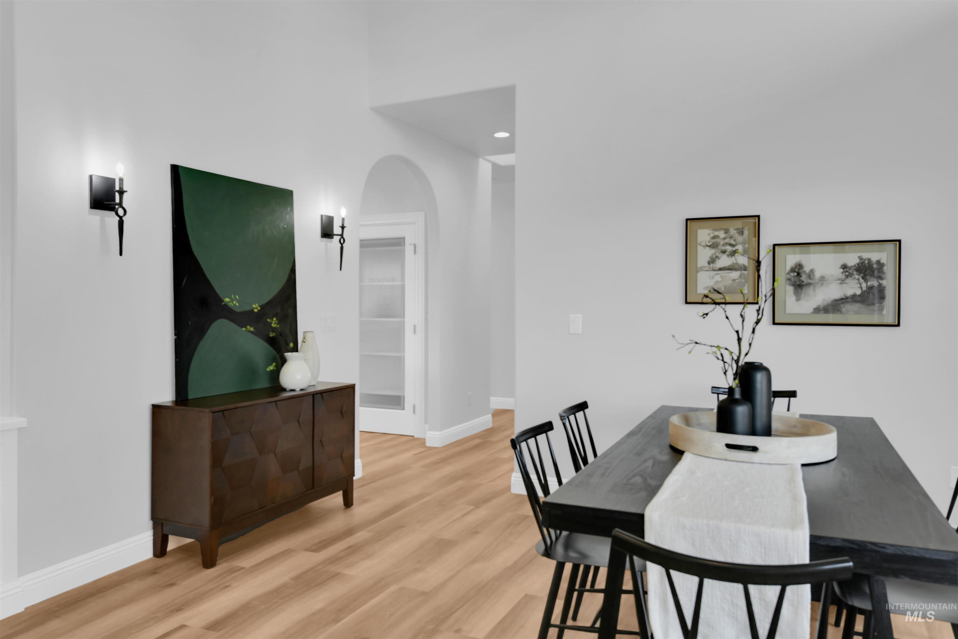 Dining room featuring arched walkways, light wood-type flooring, and recessed lighting