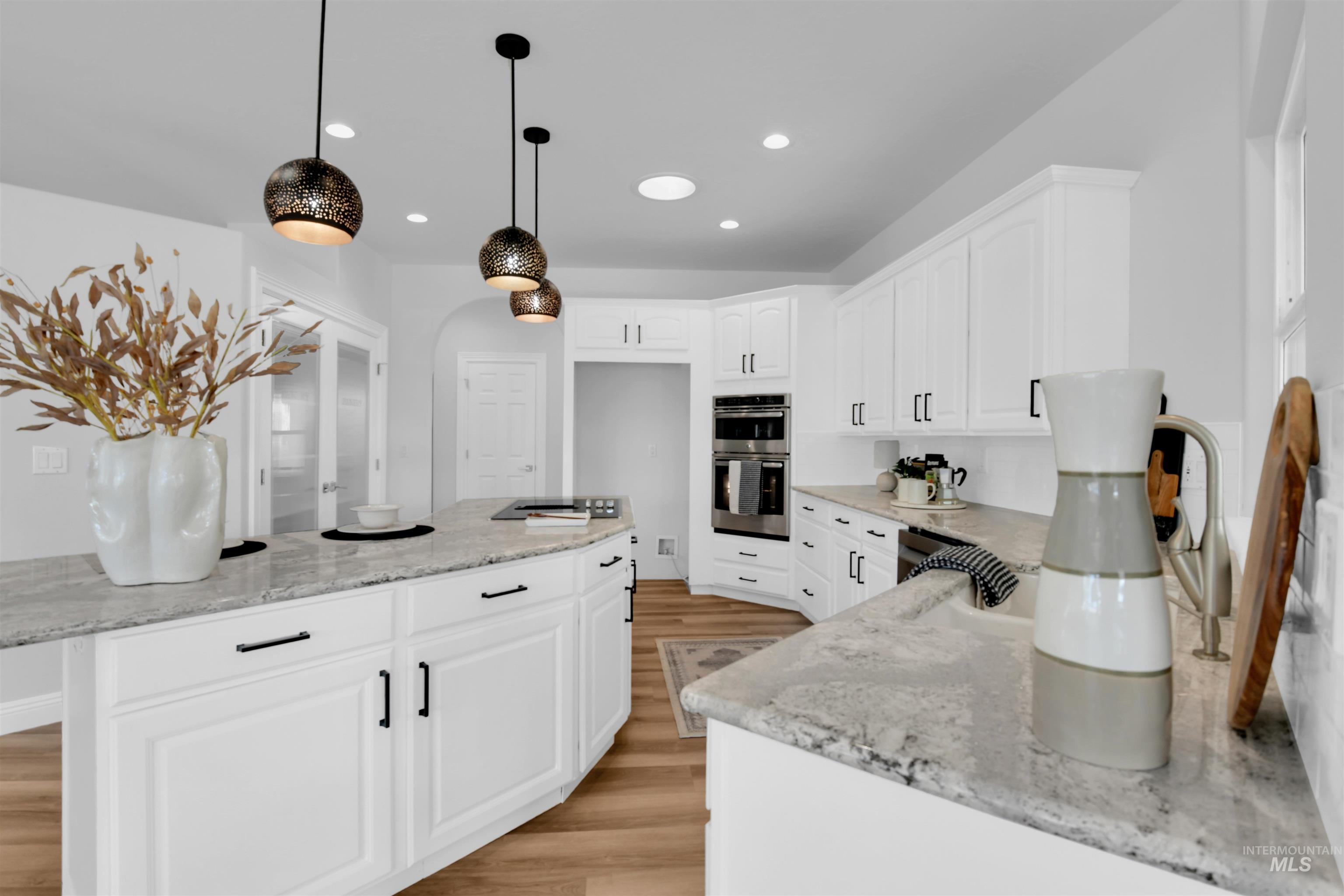 Kitchen with light stone counters, white cabinetry, pendant lighting, recessed lighting, and a center island
