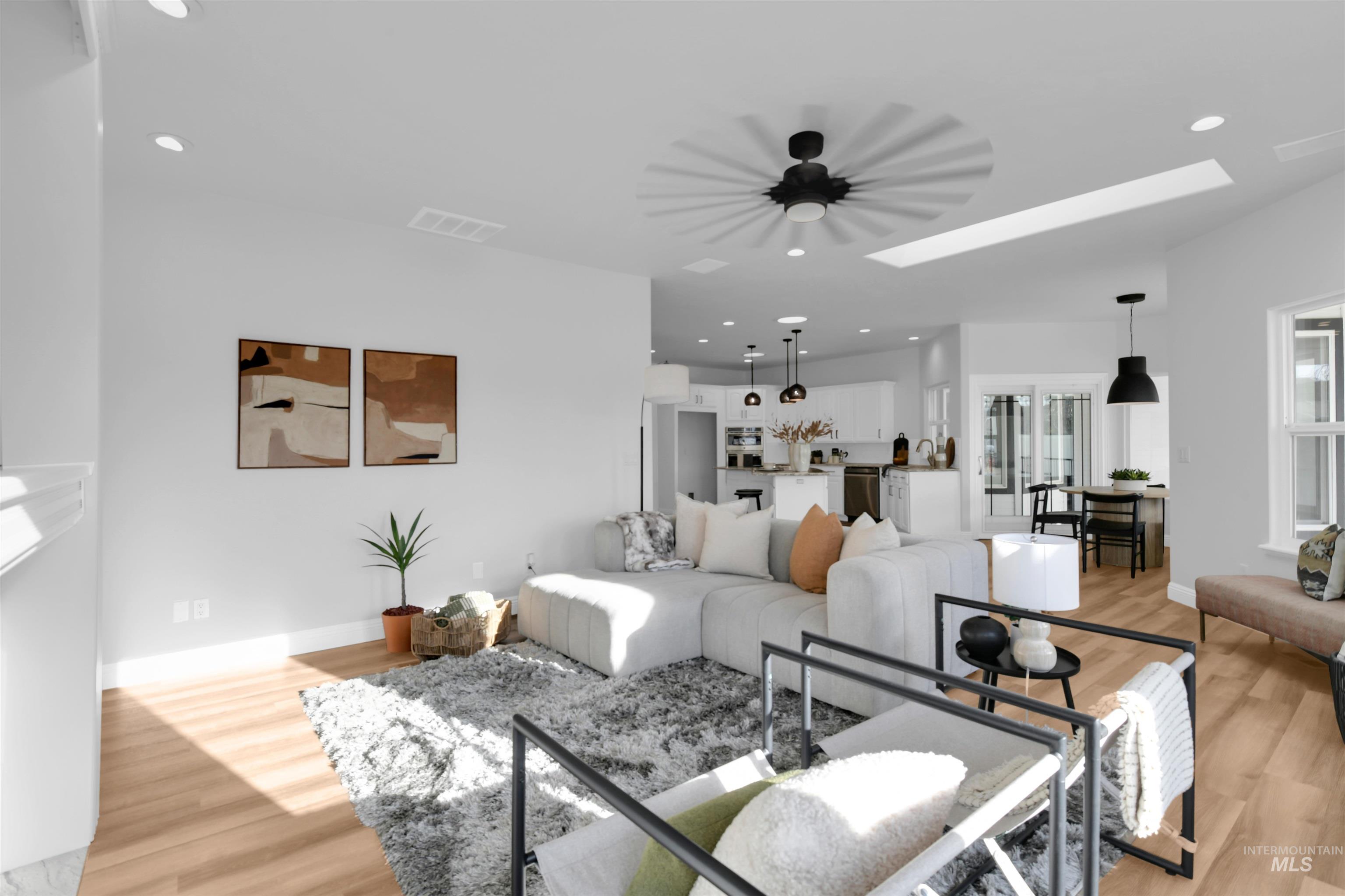 Living room with recessed lighting, light wood-style floors, and a skylight