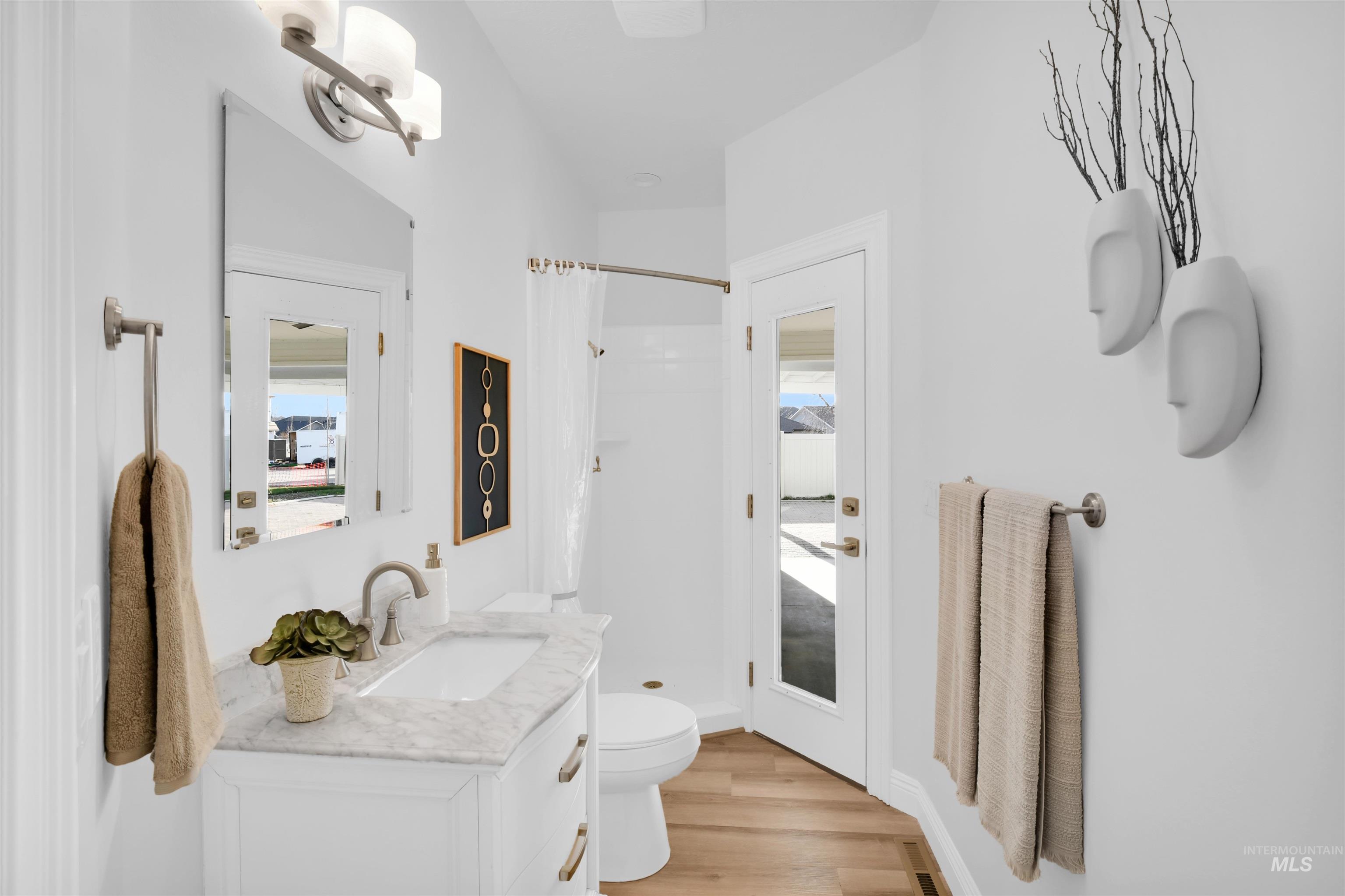 Full bath featuring a shower stall, vanity, and light wood-type flooring