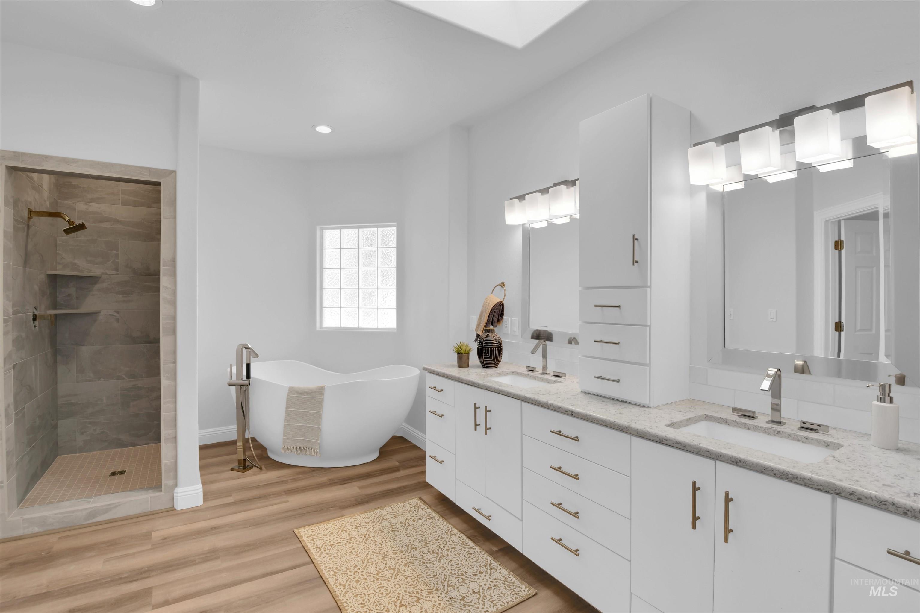 Bathroom featuring double vanity, a freestanding tub, a walk in shower, light wood-style floors, and recessed lighting