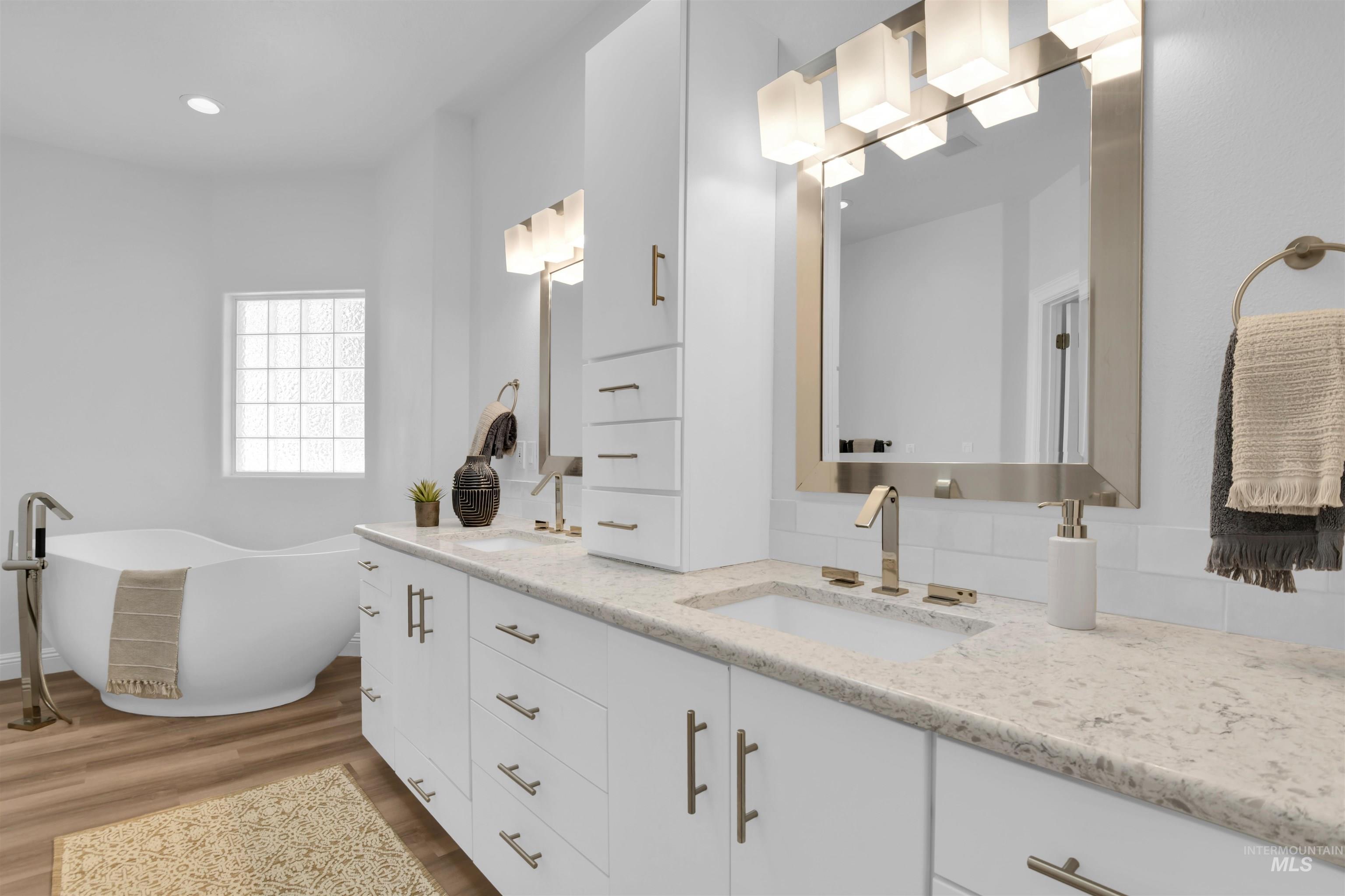 Full bath with double vanity, a soaking tub, and dark wood finished floors