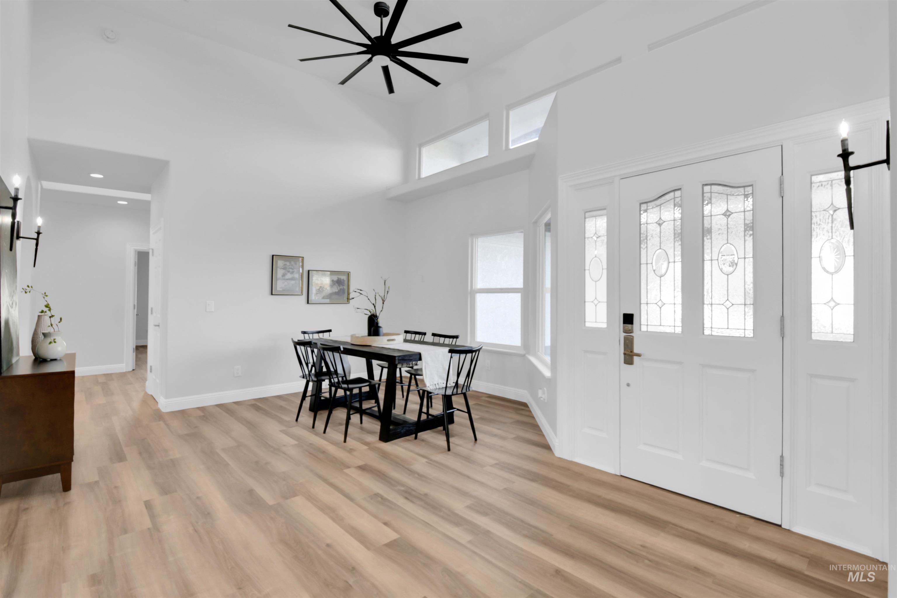 Foyer entrance featuring a towering ceiling, light wood finished floors, and ceiling fan