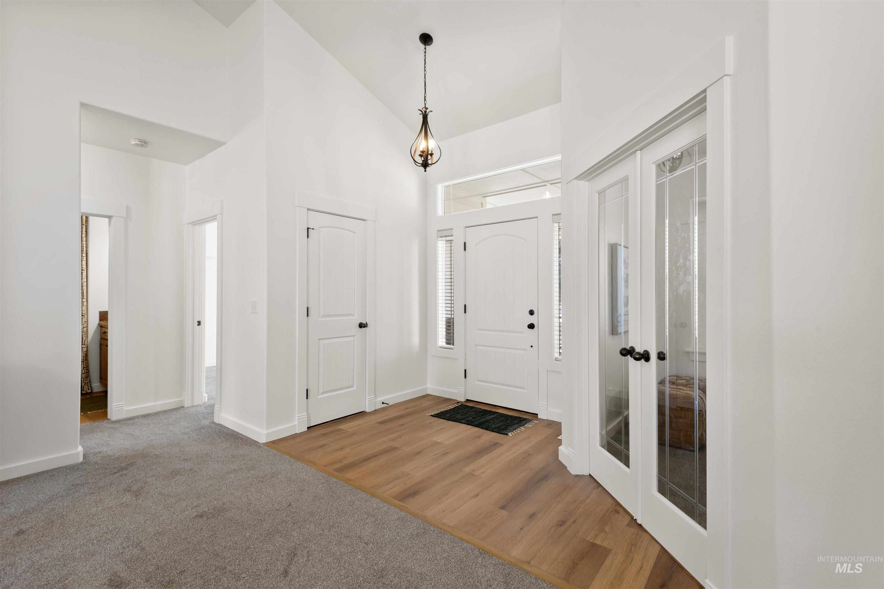 Foyer entrance with high vaulted ceiling, carpet flooring, wood finished floors, and french doors