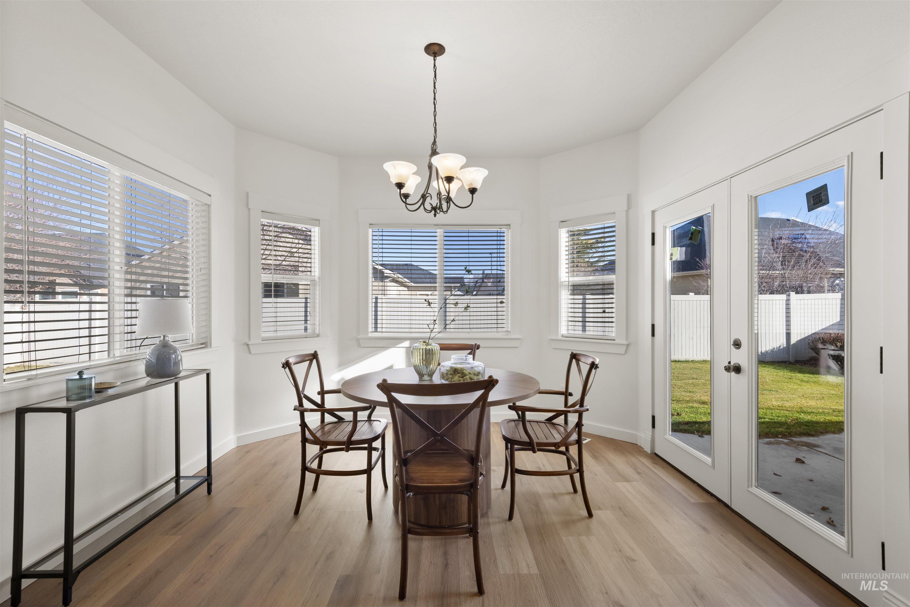 Dining room featuring light wood-type flooring, french doors, and a chandelier
