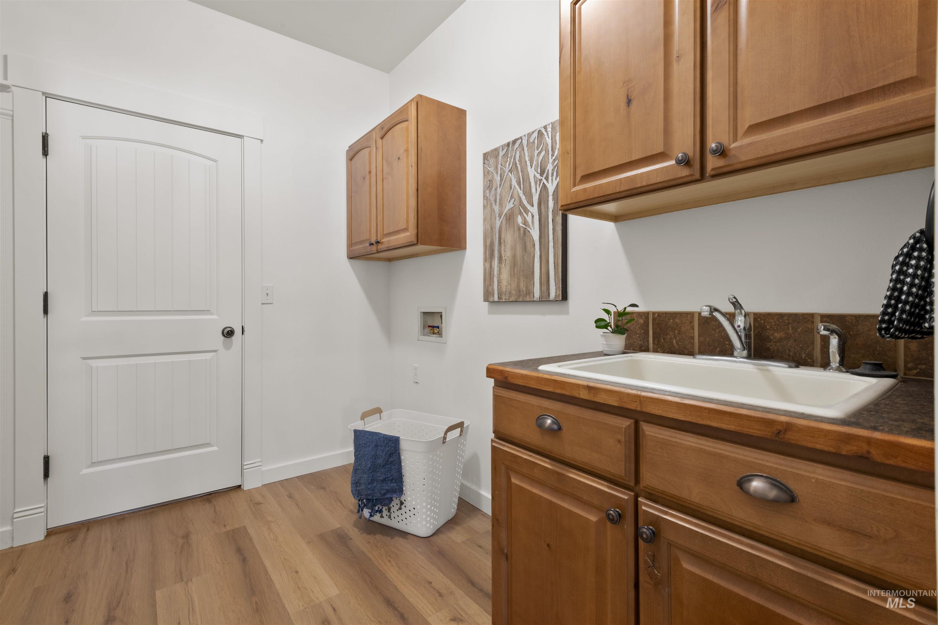 Laundry room featuring cabinet space, washer hookup, and light wood-type flooring