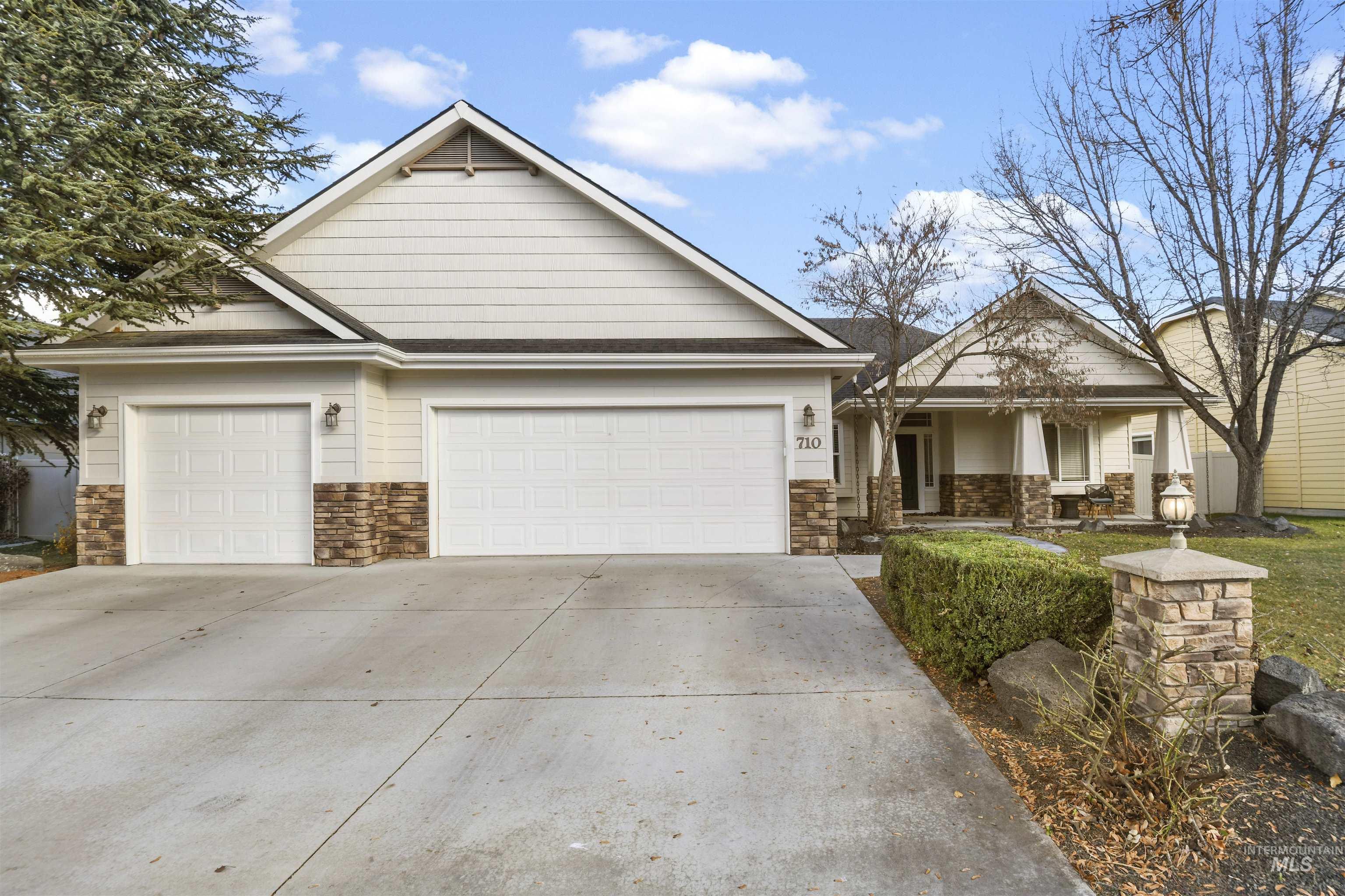 View of front of house with stone siding, concrete driveway, a porch, and a garage