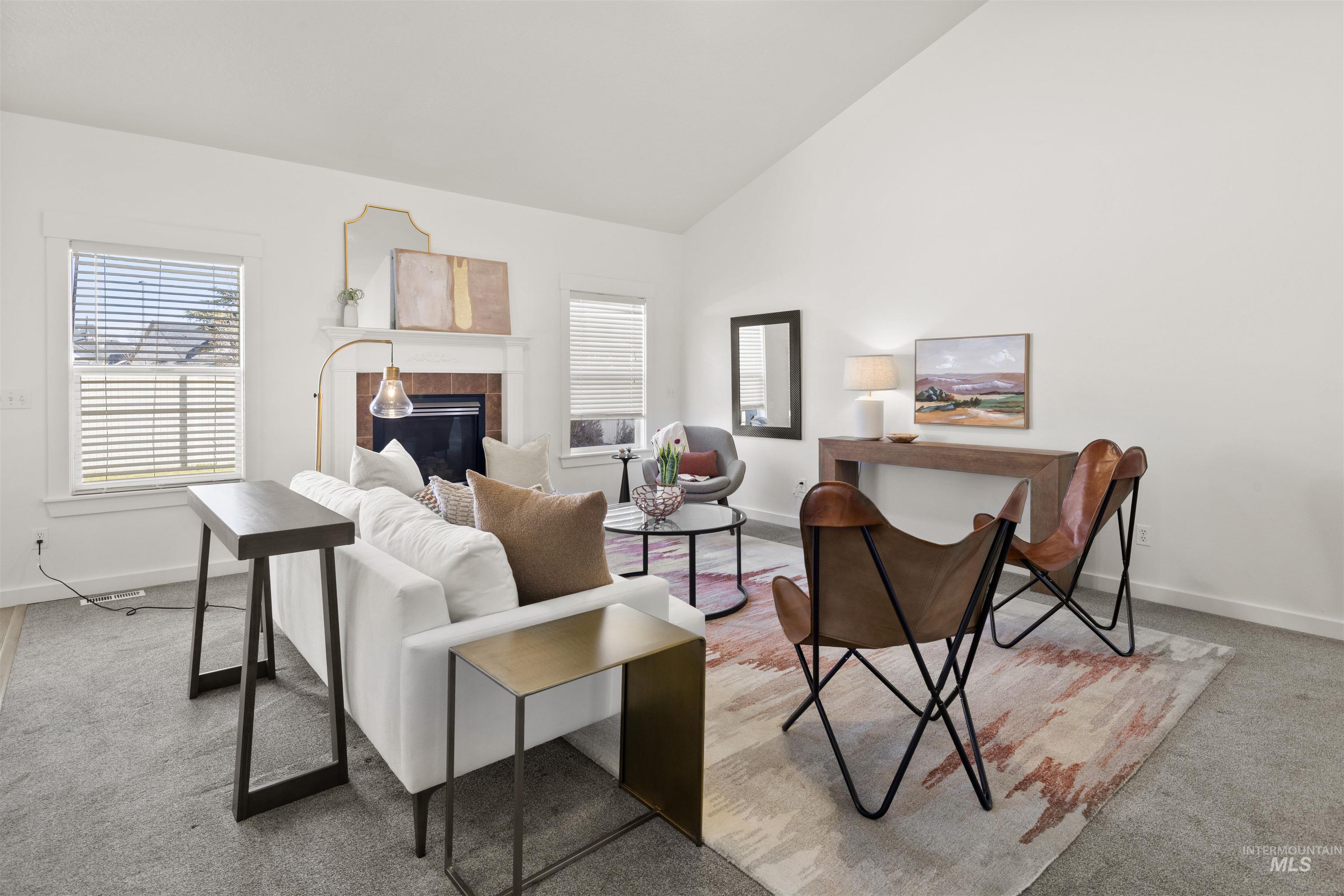 Living area featuring plenty of natural light, a tiled fireplace, high vaulted ceiling, and light colored carpet