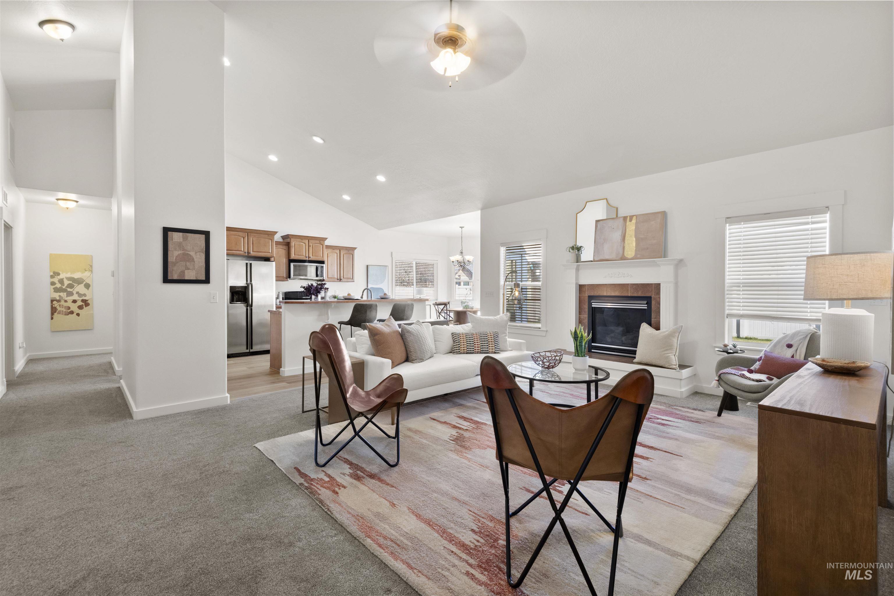 Living room with light colored carpet, a tiled fireplace, high vaulted ceiling, recessed lighting, and ceiling fan