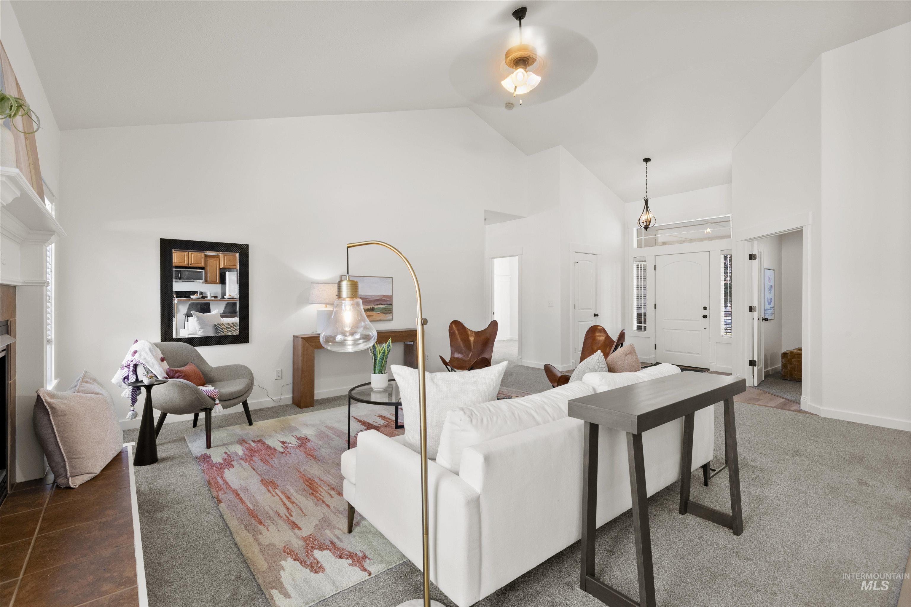 Living room featuring a fireplace, high vaulted ceiling, and a ceiling fan