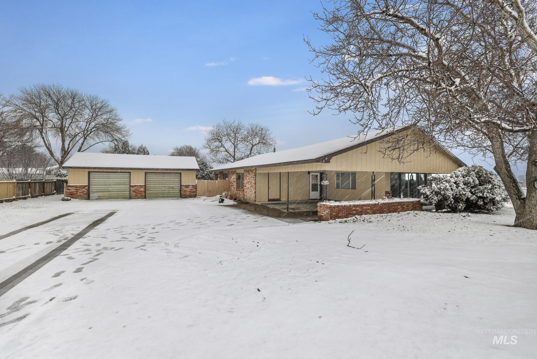 View of snow covered exterior with an outdoor structure and a detached garage