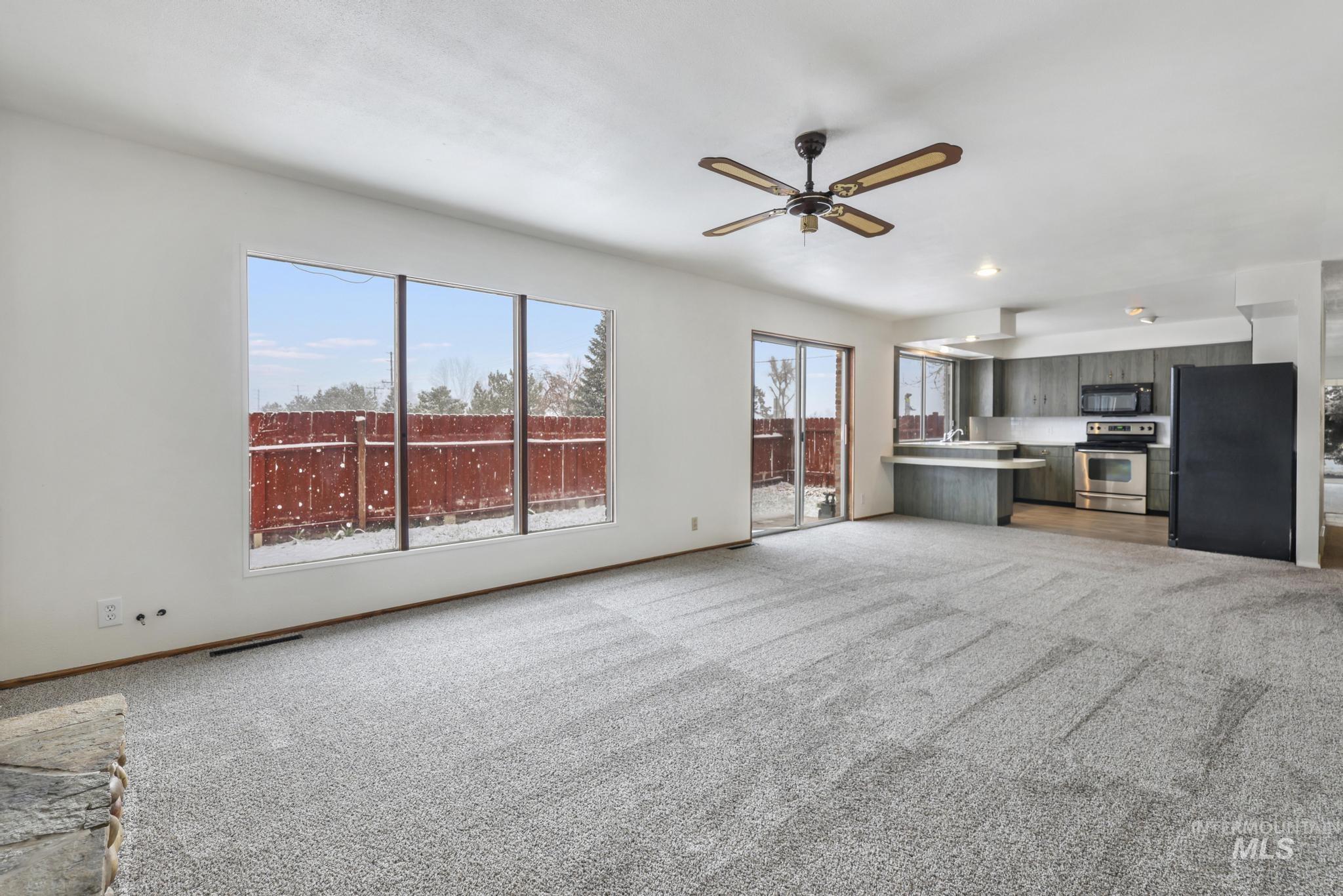 Unfurnished living room featuring light colored carpet and a ceiling fan