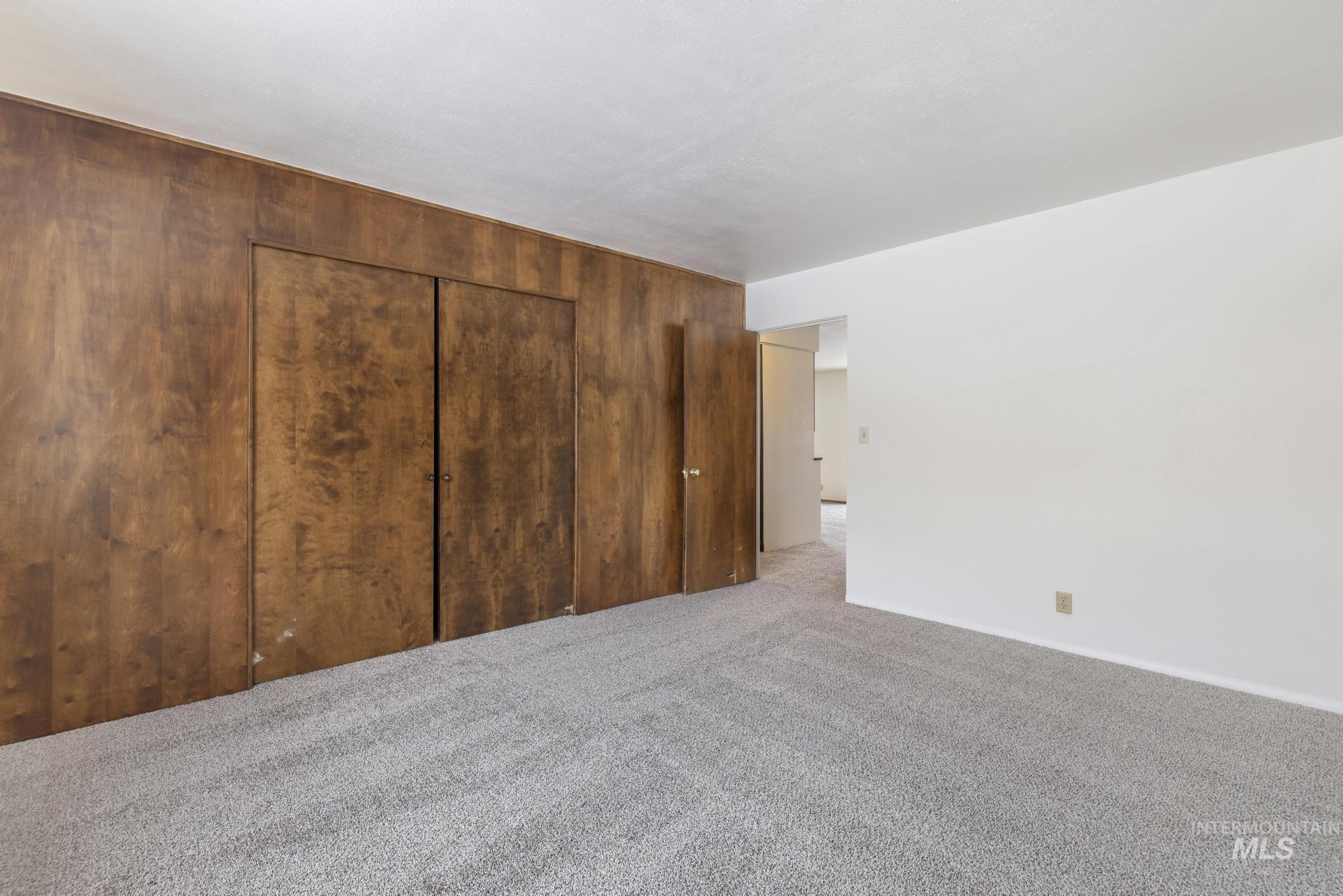 Unfurnished bedroom with carpet flooring, a closet, and wood walls