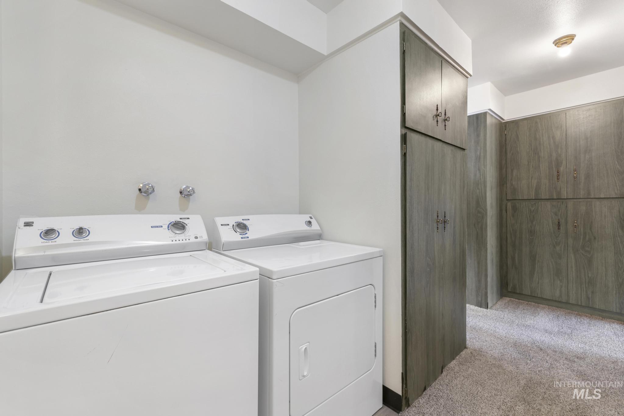 Laundry room featuring light colored carpet and separate washer and dryer