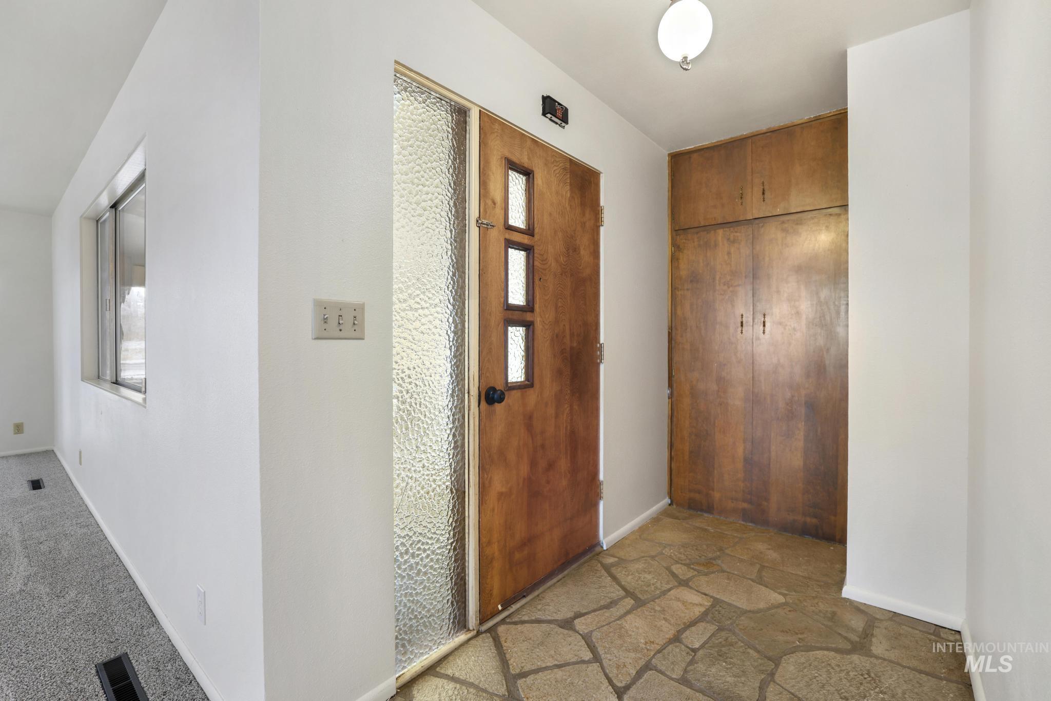 Foyer featuring baseboards and stone finish flooring