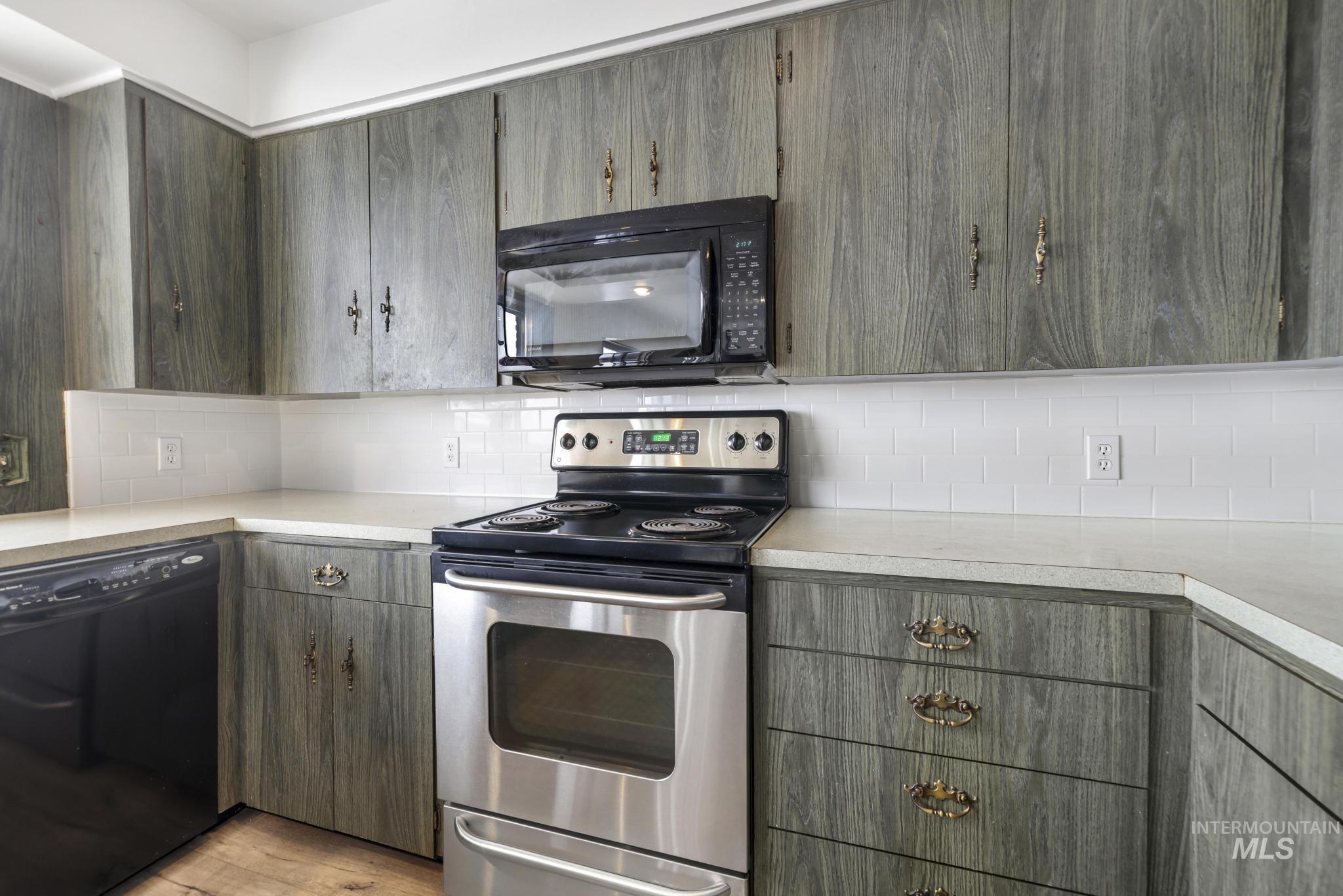 Kitchen featuring black appliances, light countertops, decorative backsplash, and light wood-type flooring